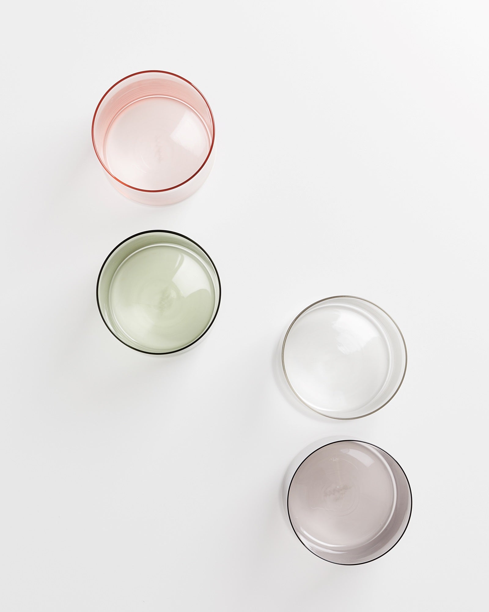 Vier verschiedenfarbige, durchsichtige Gläser auf einem weißen Hintergrund.