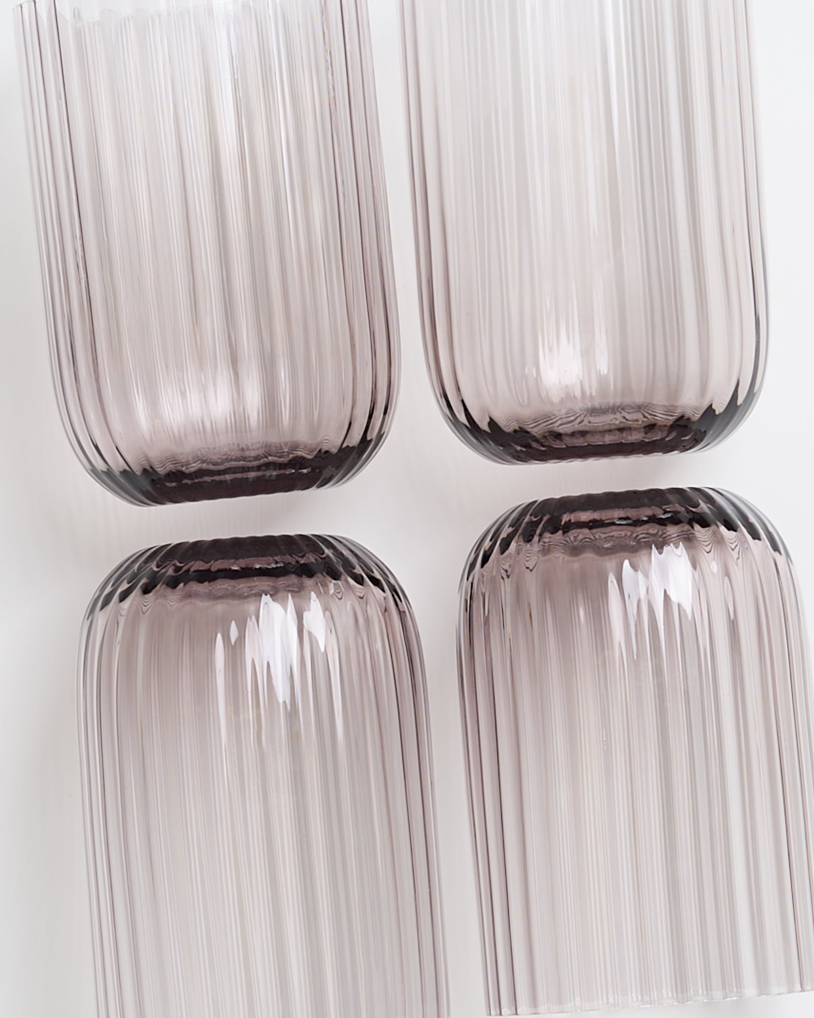 Vier strukturierte, transparente Gläser in hellem Violett, von oben gesehen, auf einem weißen Hintergrund.