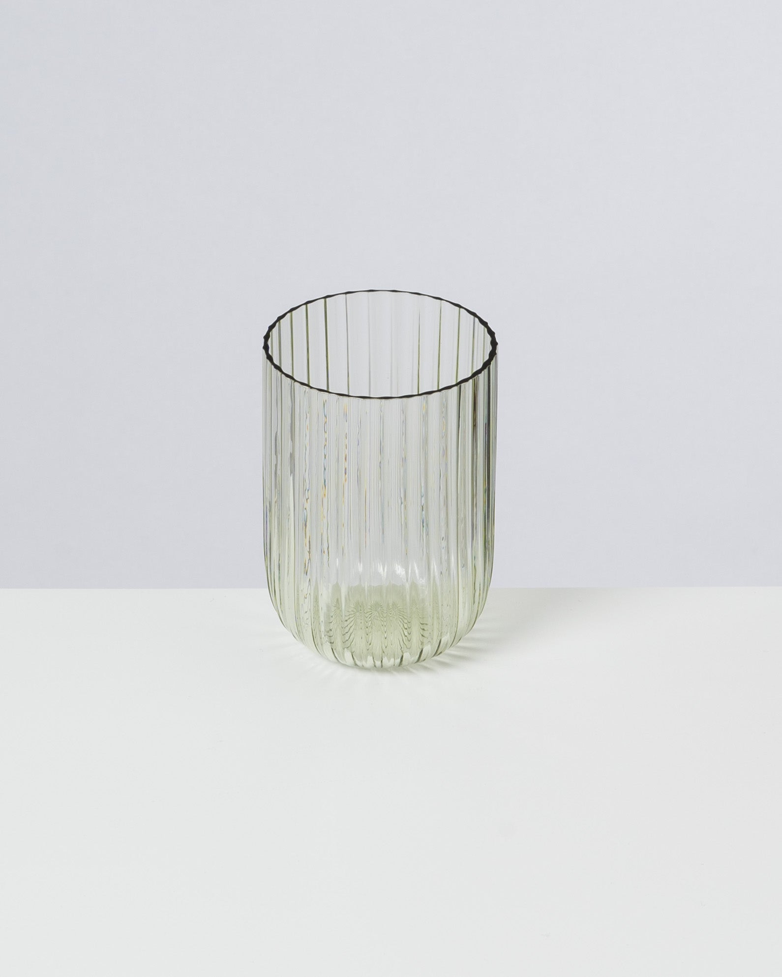 Klare, geriffelte Glasschale vor einem neutralen Hintergrund auf weißem Tisch platziert.