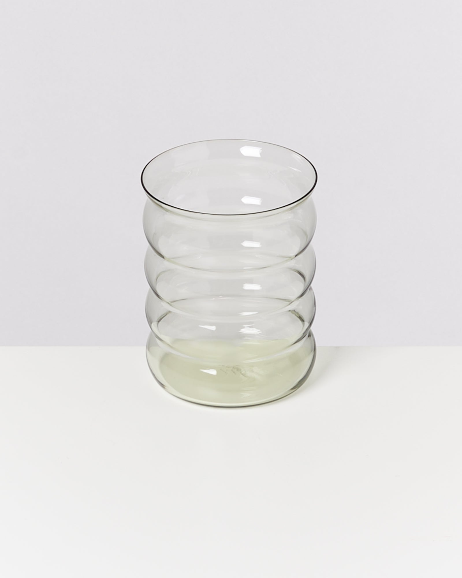 Transparente, geriffelte Glasvase mit runder Form auf weißem Hintergrund.