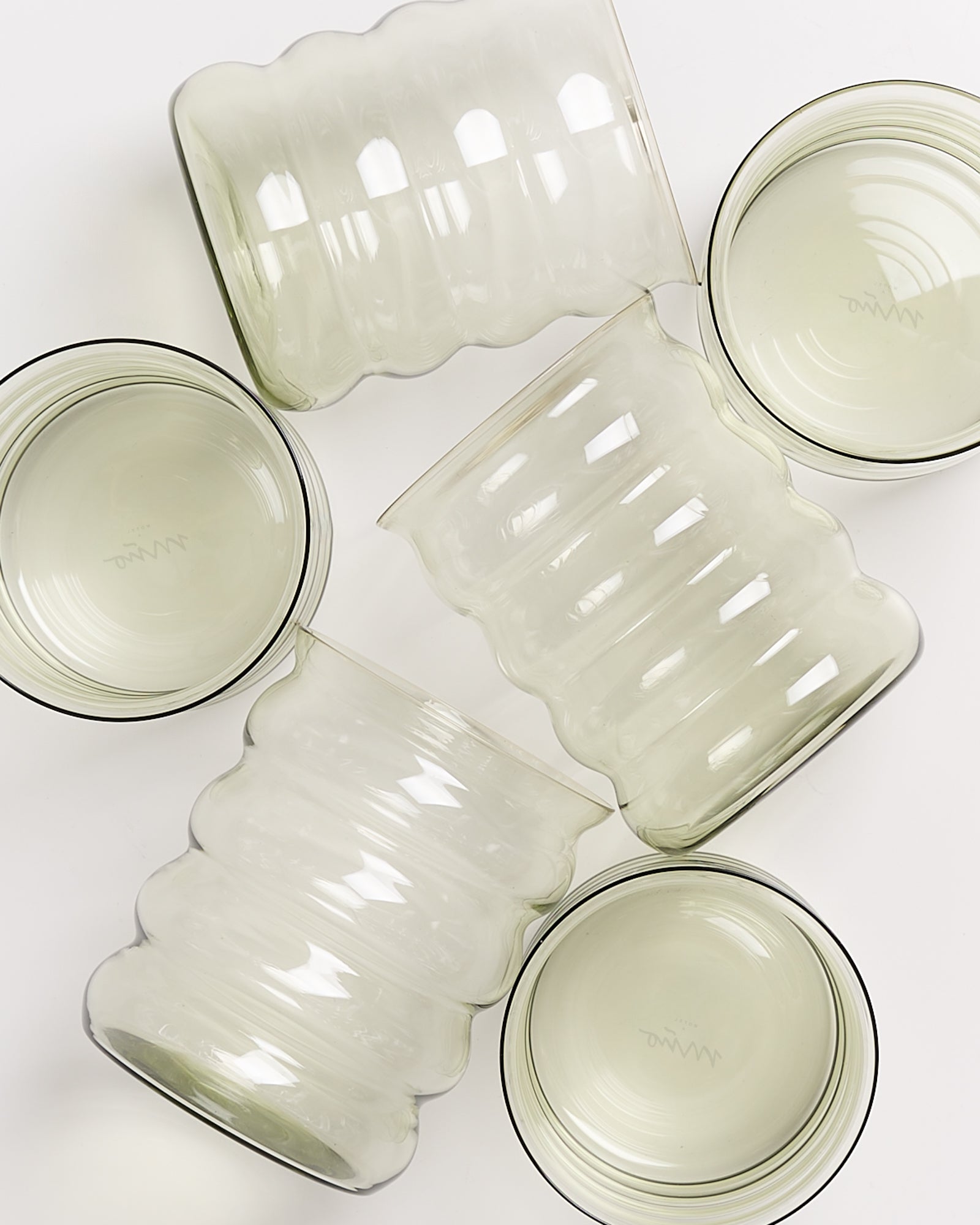 Fünf gewölbte, transparente Gläser in verschiedenen Positionen auf einem weißen Hintergrund.