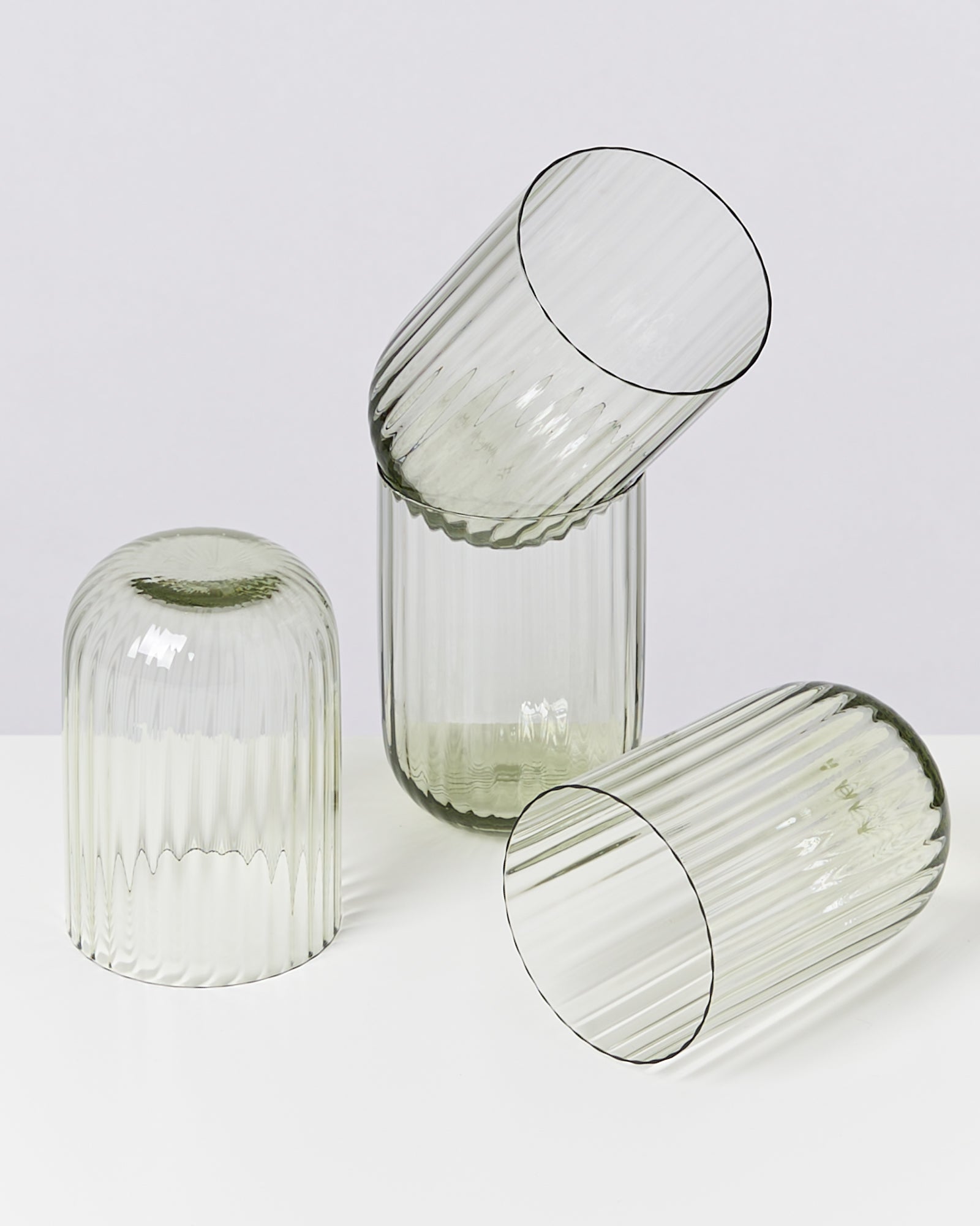 Drei transparente, geriffelte Glasvasen in verschiedenen Winkeln auf einem weißen Hintergrund angeordnet.