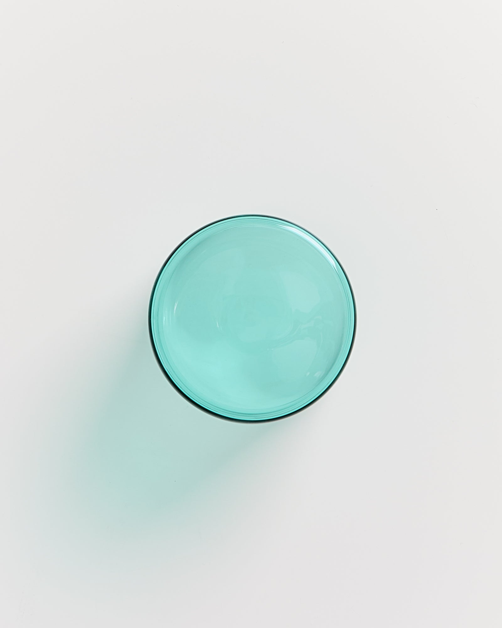 Türkise Glasschale vor einem weißen Hintergrund, von oben gesehen.