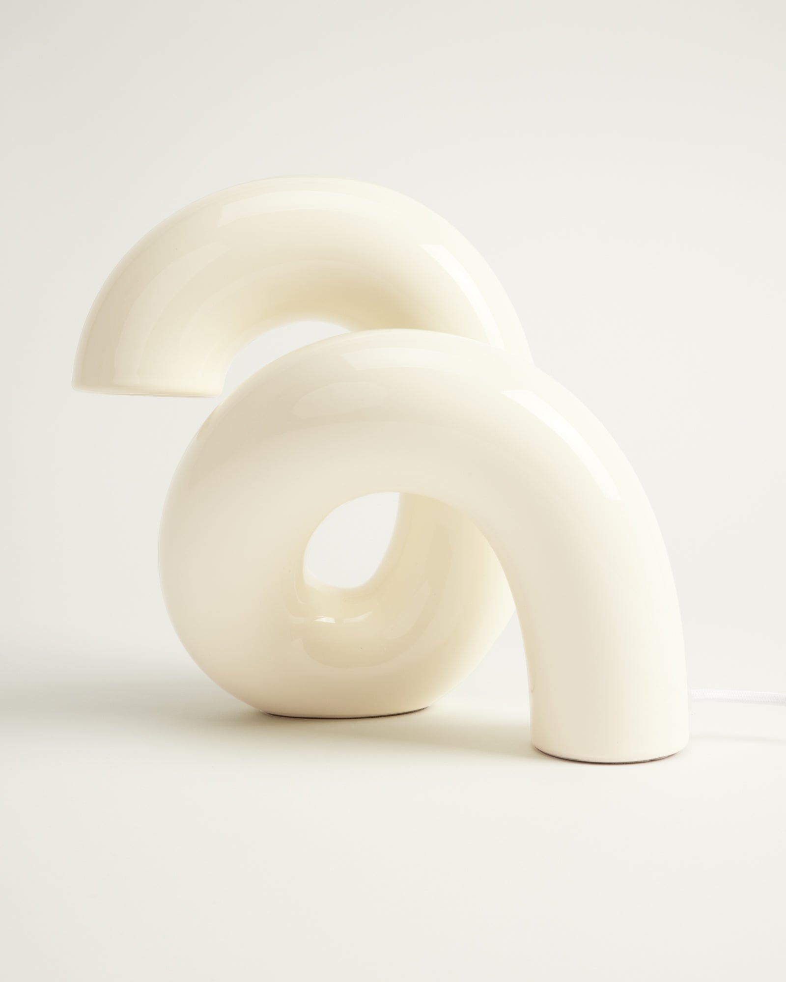 Weiße, abstrakte Skulptur mit geschwungenen Formen auf hellem Hintergrund.