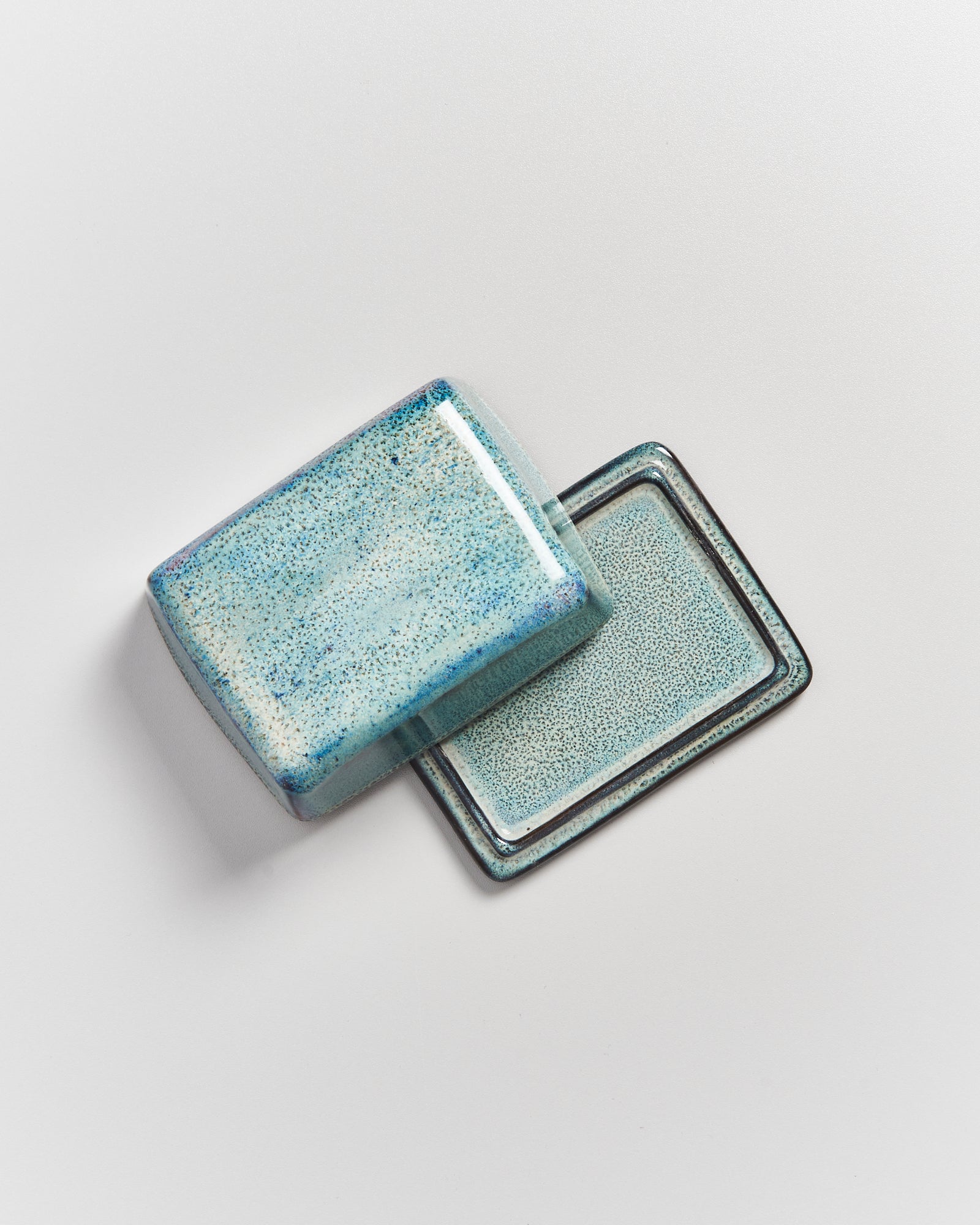 Blaue Keramikseifenschale mit Deckel auf weißem Hintergrund.