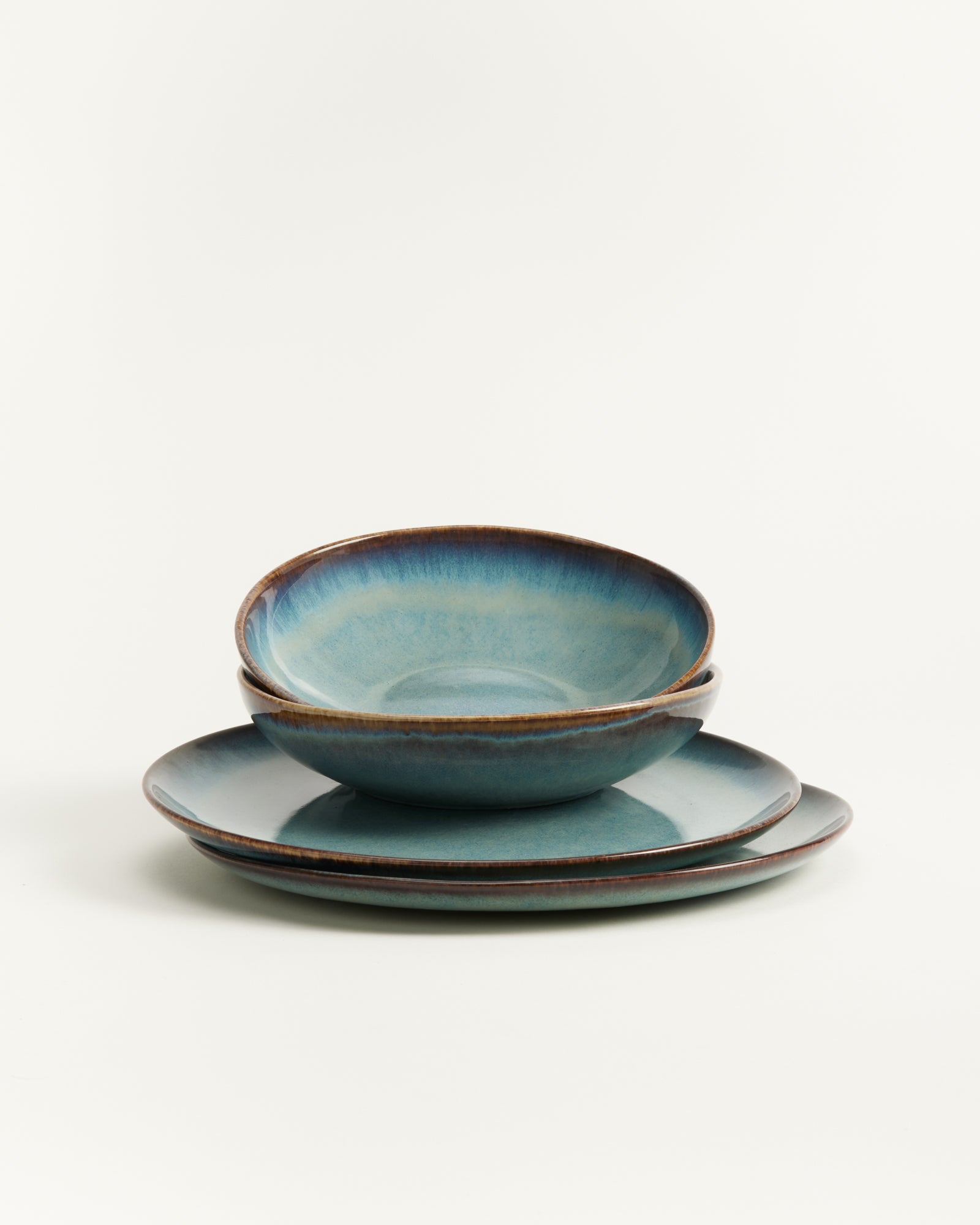 Drei übereinander gestapelte blau-grüne Keramikteller auf weißem Hintergrund.