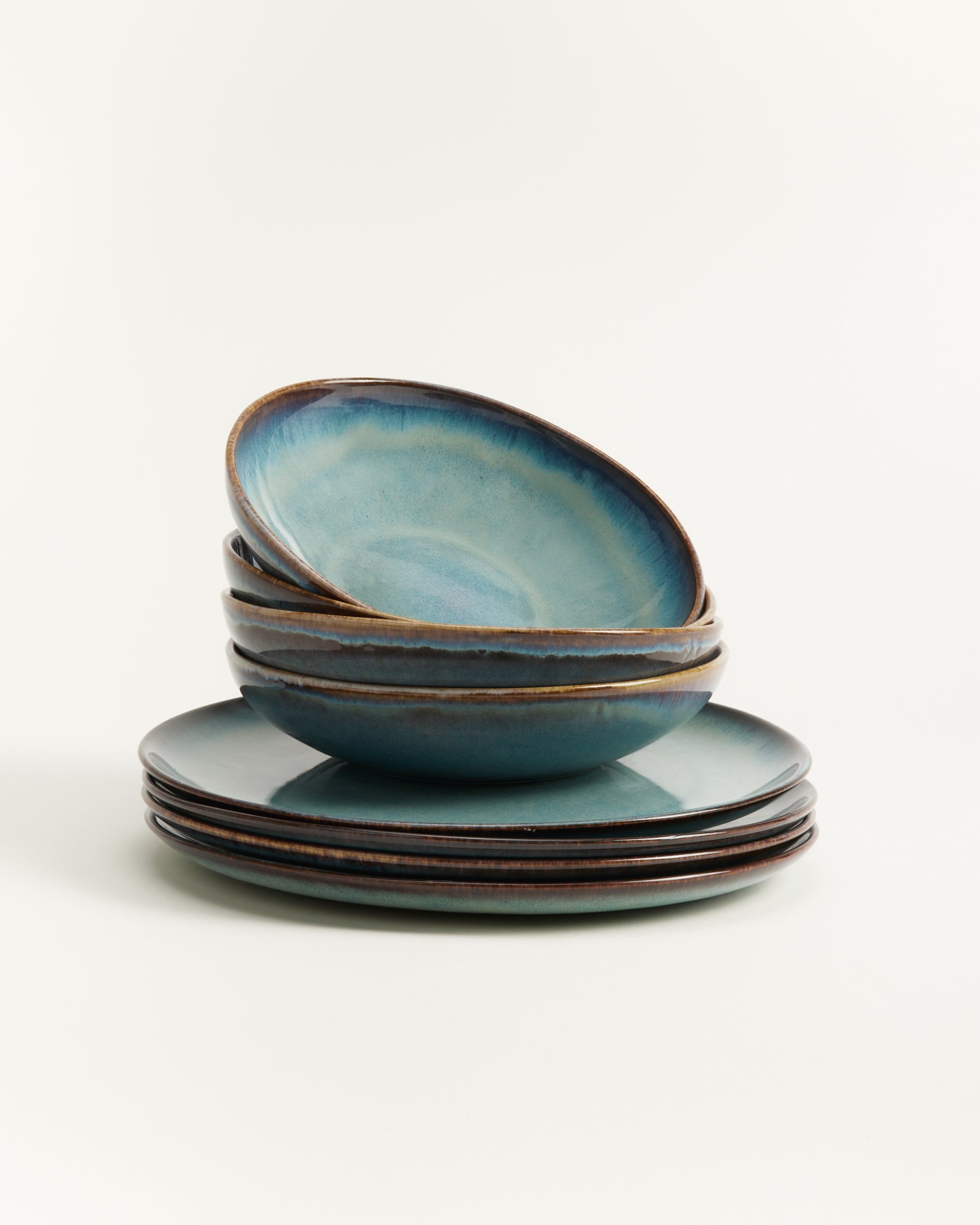 Ein Stapel aus vier blauen, rustikal glasierten Schalen und Tellern auf weißem Hintergrund.