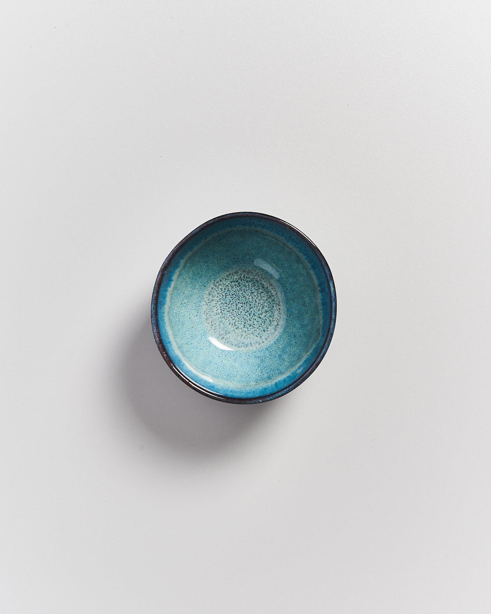 Kleine türkisfarbene Keramikschale auf weißem Hintergrund.