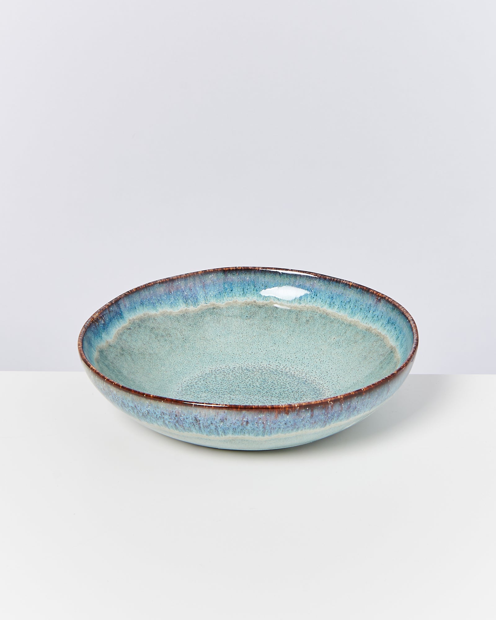 Keramikschale mit blau-grüner Glasur auf weißem Hintergrund.