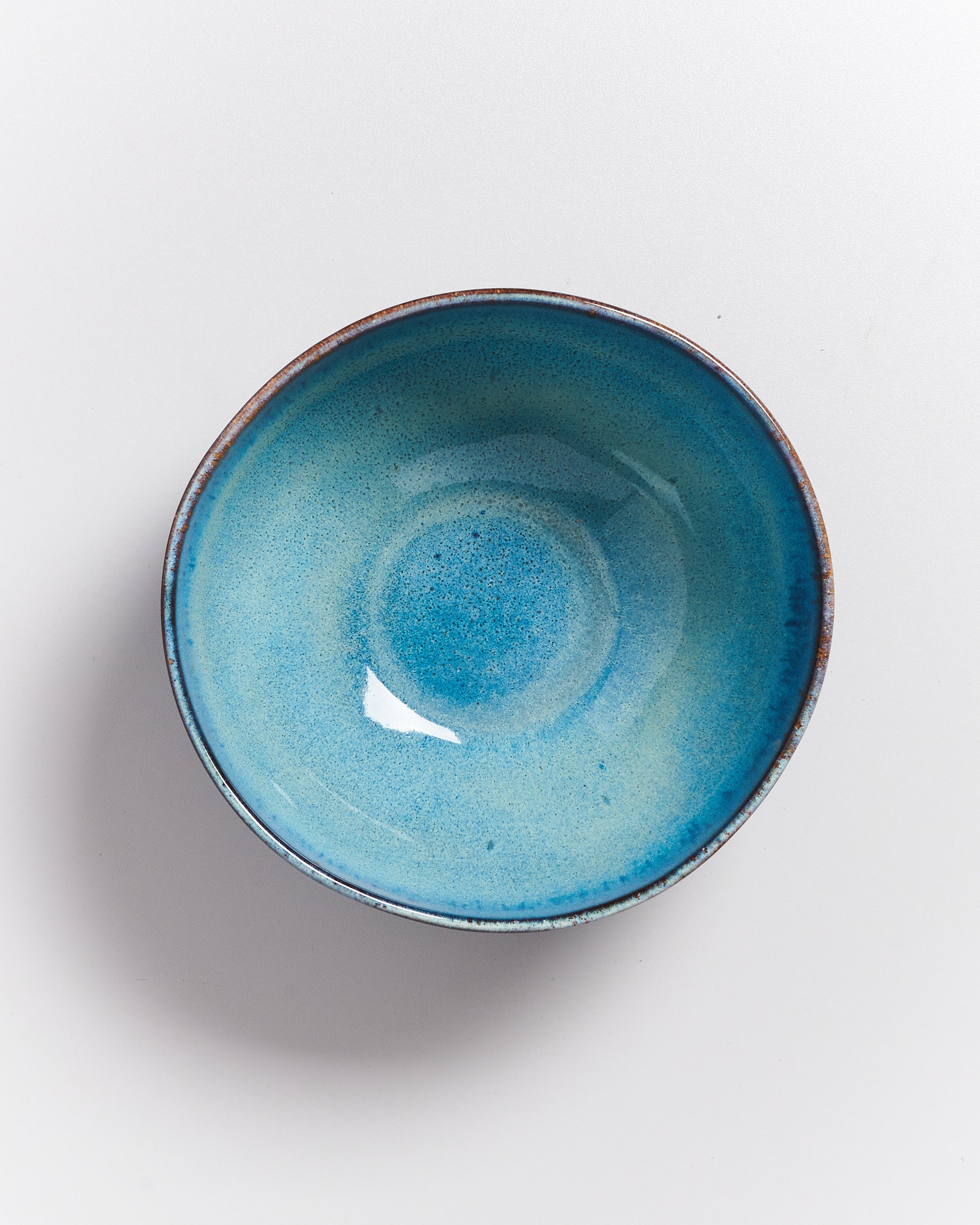 Blaue Keramikschüssel mit glatter Textur auf einem weißen Hintergrund.