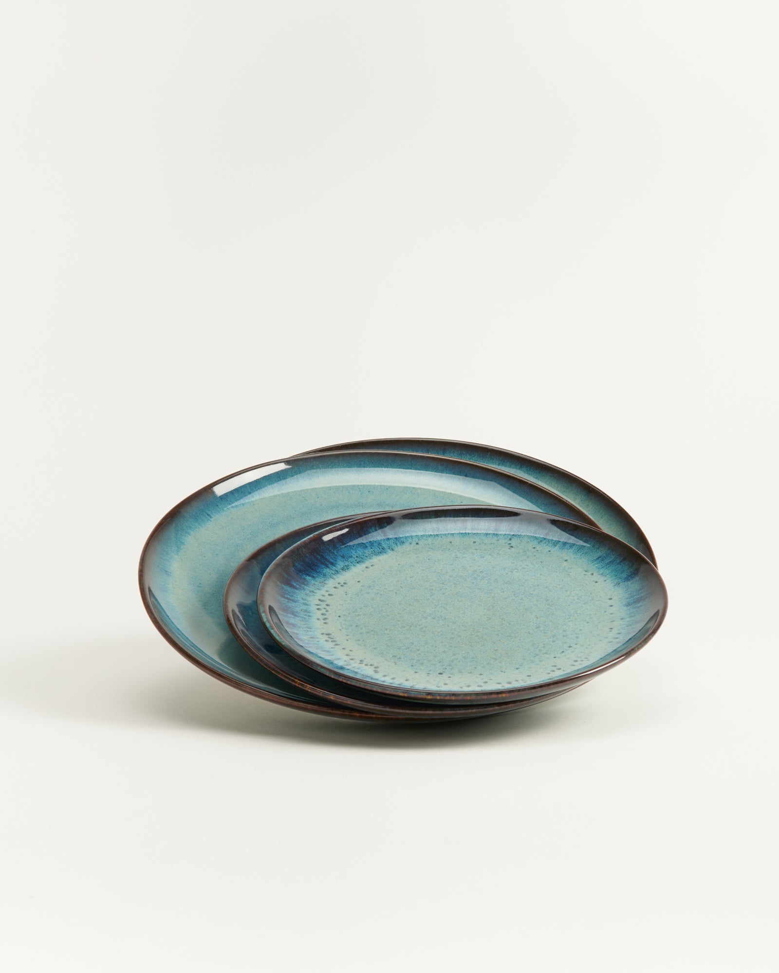 Zwei übereinander gestapelte Teller in Blau- und Grüntönen mit leicht glänzender Oberfläche auf hellem Hintergrund.