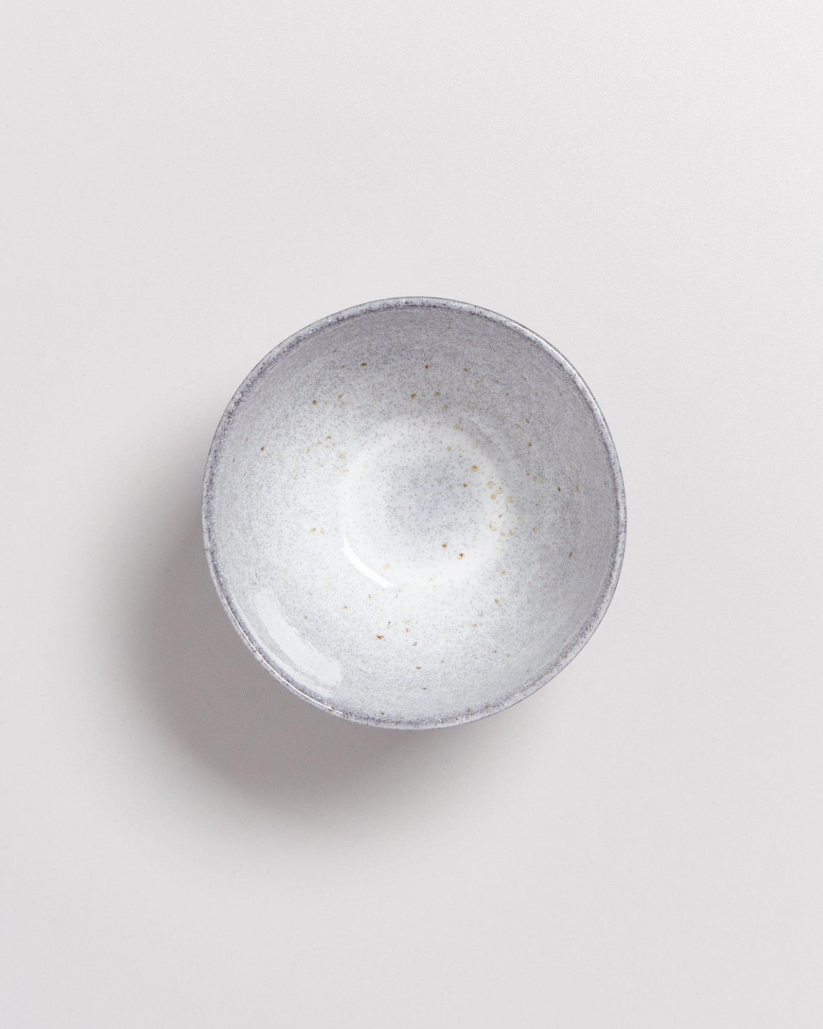 Keramikschale mit grauem und cremefarbenem Muster auf hellem Hintergrund.