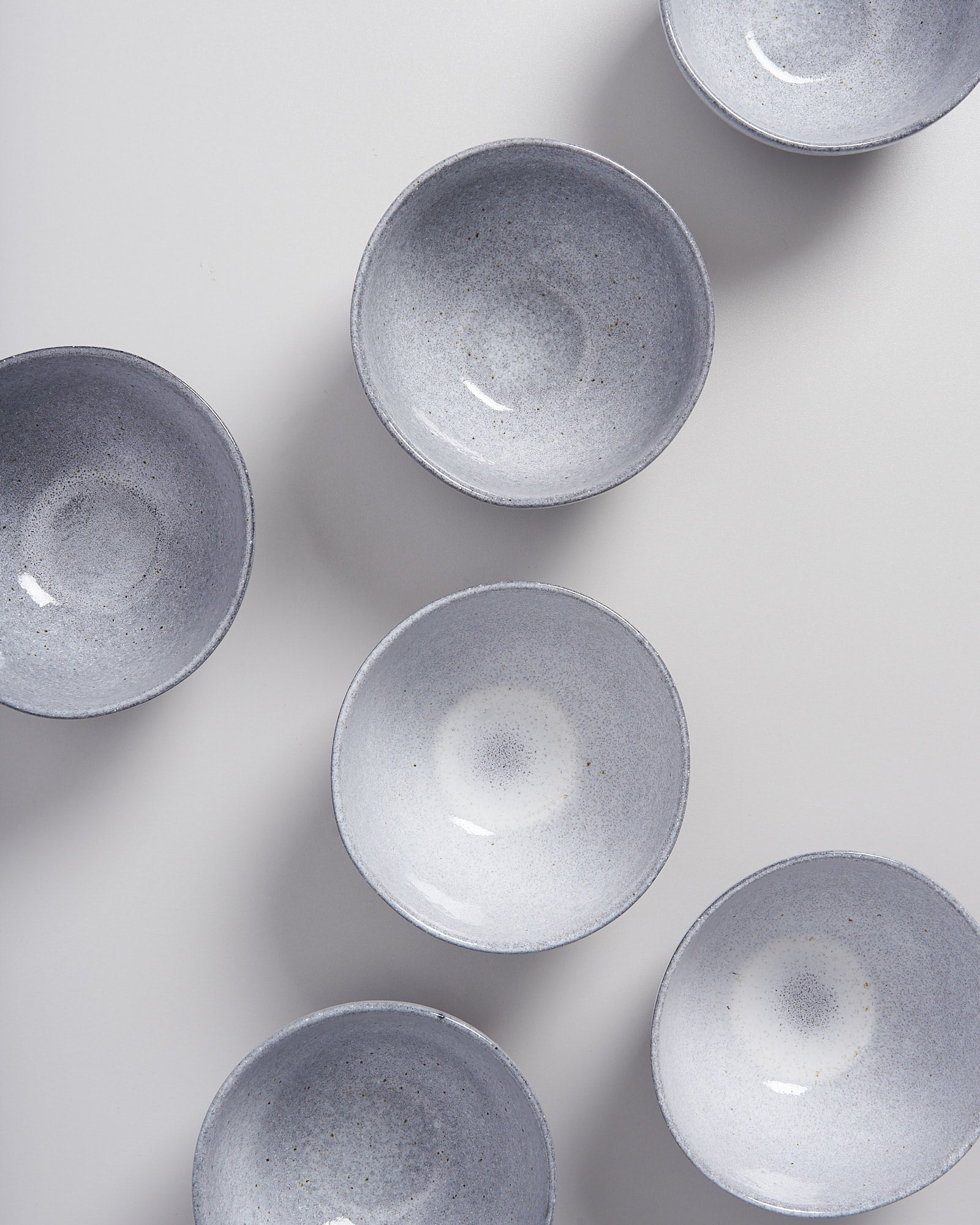 Sechs graue Schalen sind gleichmäßig auf einem weißen Hintergrund angeordnet.