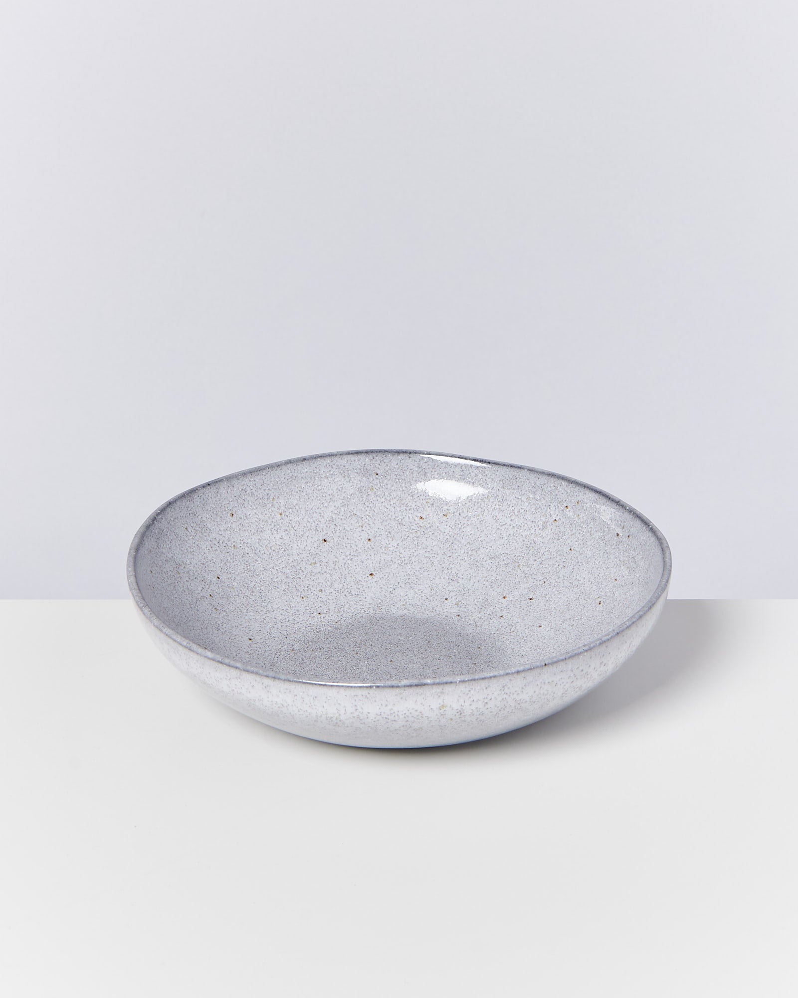 Grauer, glatter Keramikteller mit leichtem Glanz auf einem weißen Hintergrund.