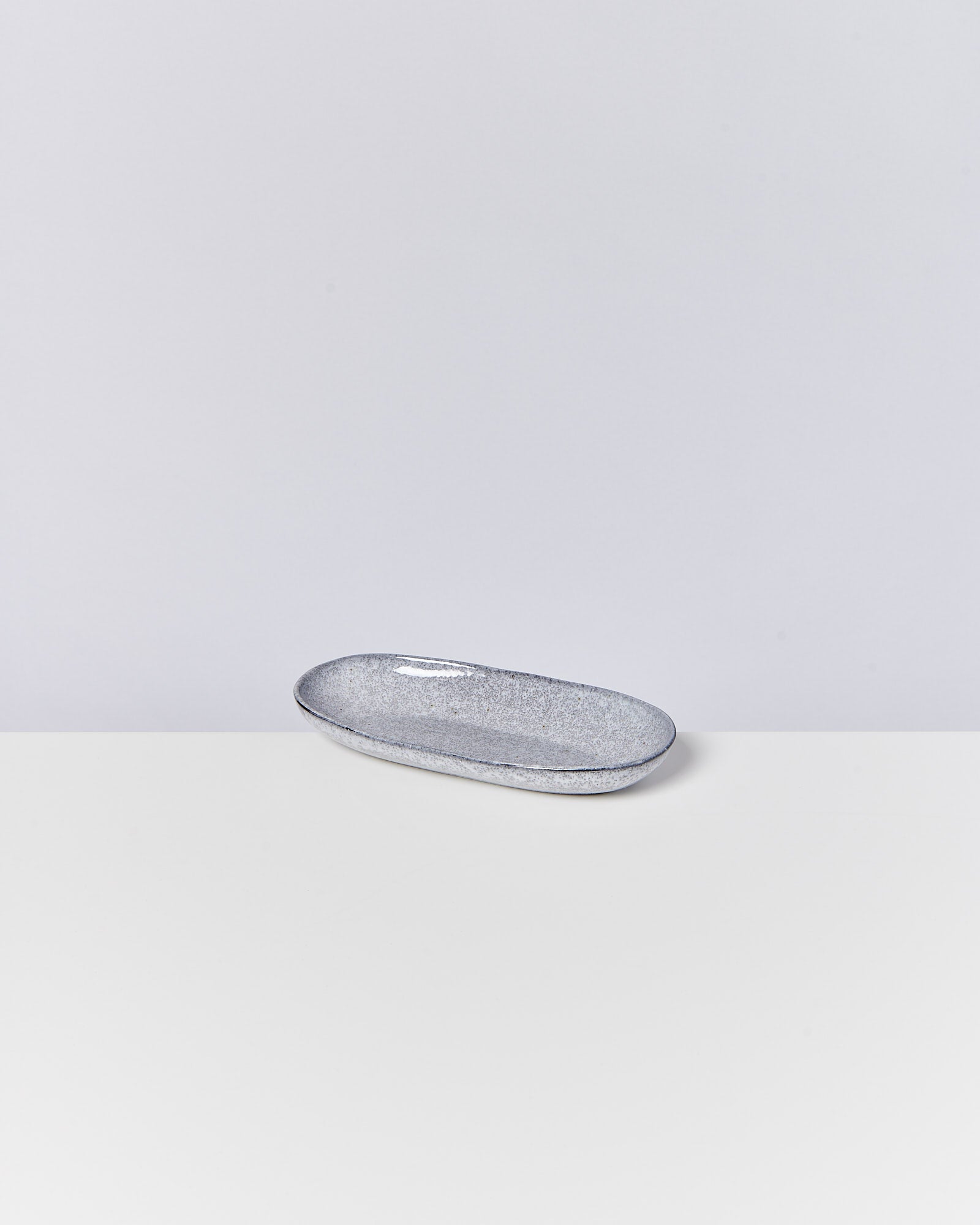 Graue, ovale Schale mit gesprenkelter Textur auf einem weißen Hintergrund.