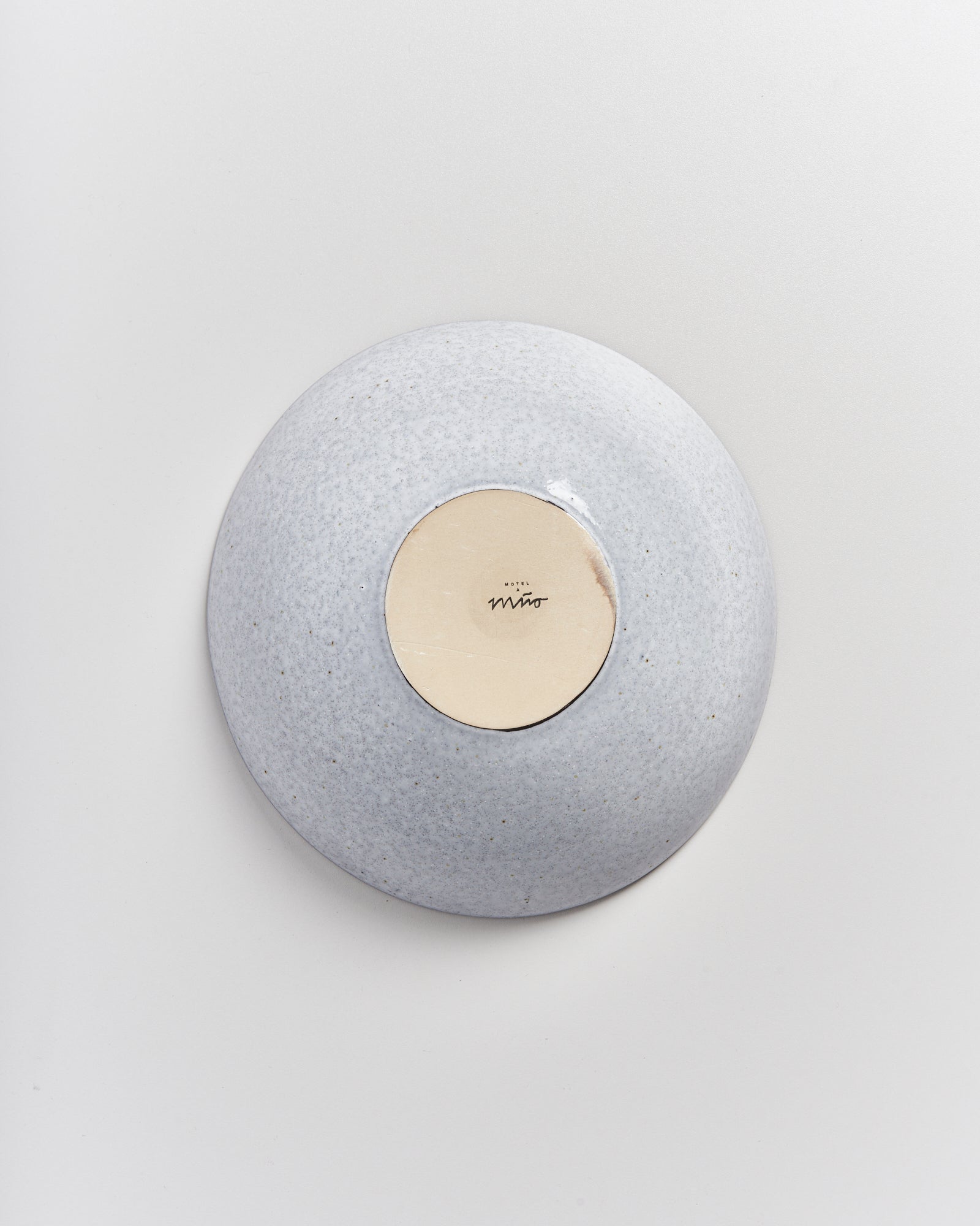 Graue Keramikschale, von oben fotografiert, mit einem beigen Boden und einer kleinen schwarzen Markierung in der Mitte.