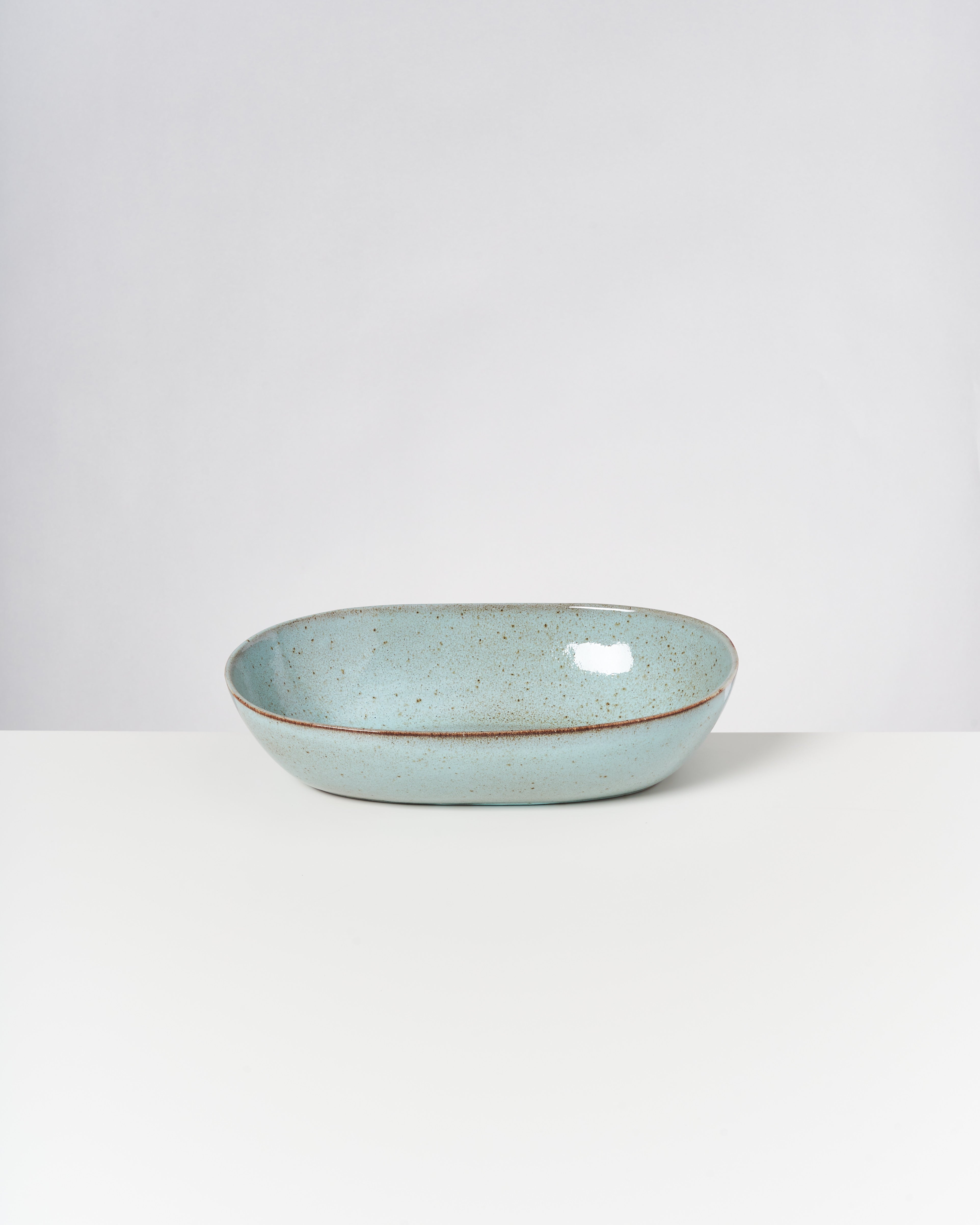 Eine blau-graue, ovale Keramikschale auf einem weißen Hintergrund.