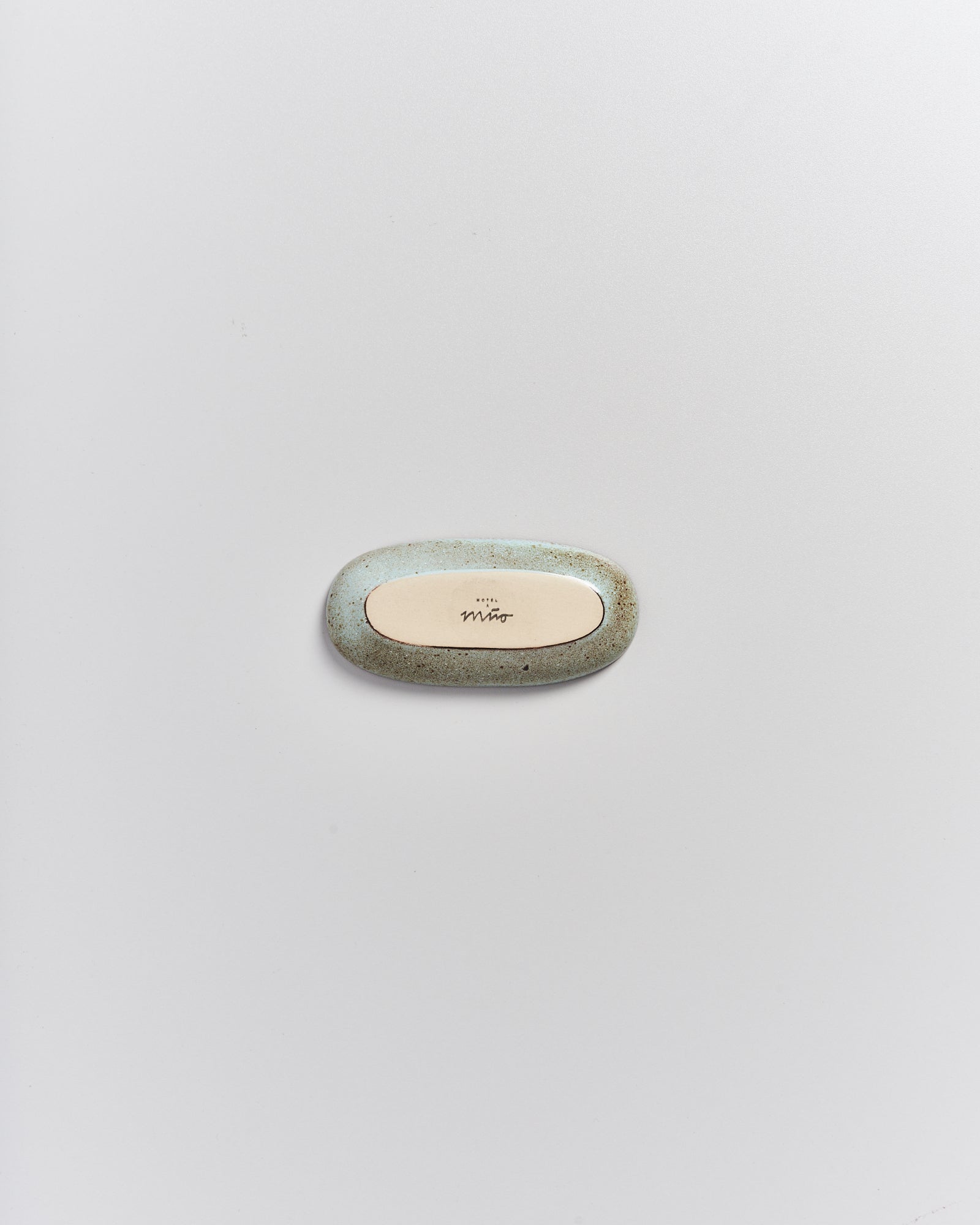 Ovale, grünlich-marmorierte Seife mit einer beigen Fläche und Aufschrift in der Mitte, liegt auf weißem Hintergrund.