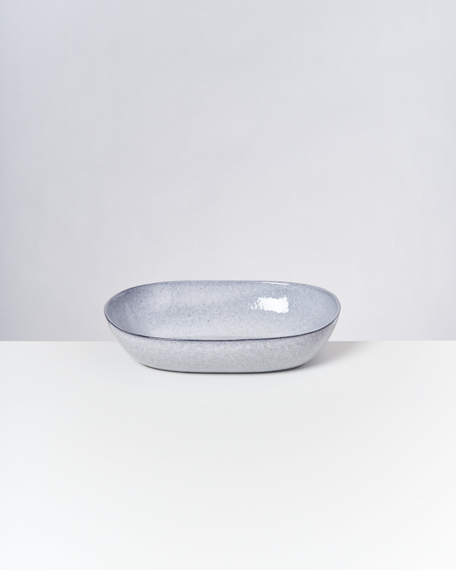 Grauer, ovaler Keramikteller auf einem weißen Hintergrund.