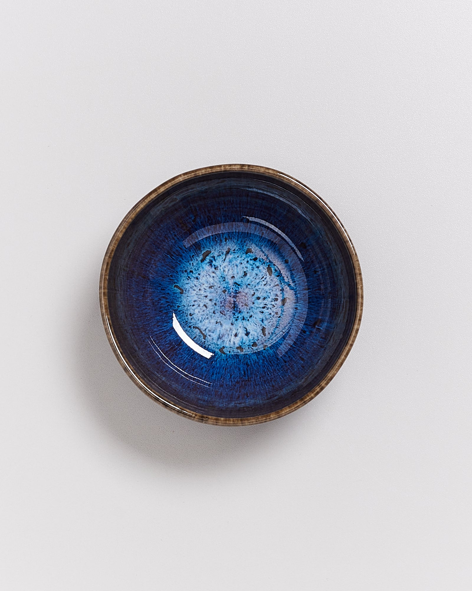 Keramikschale mit blauem, gesprenkeltem Muster auf weißem Hintergrund.