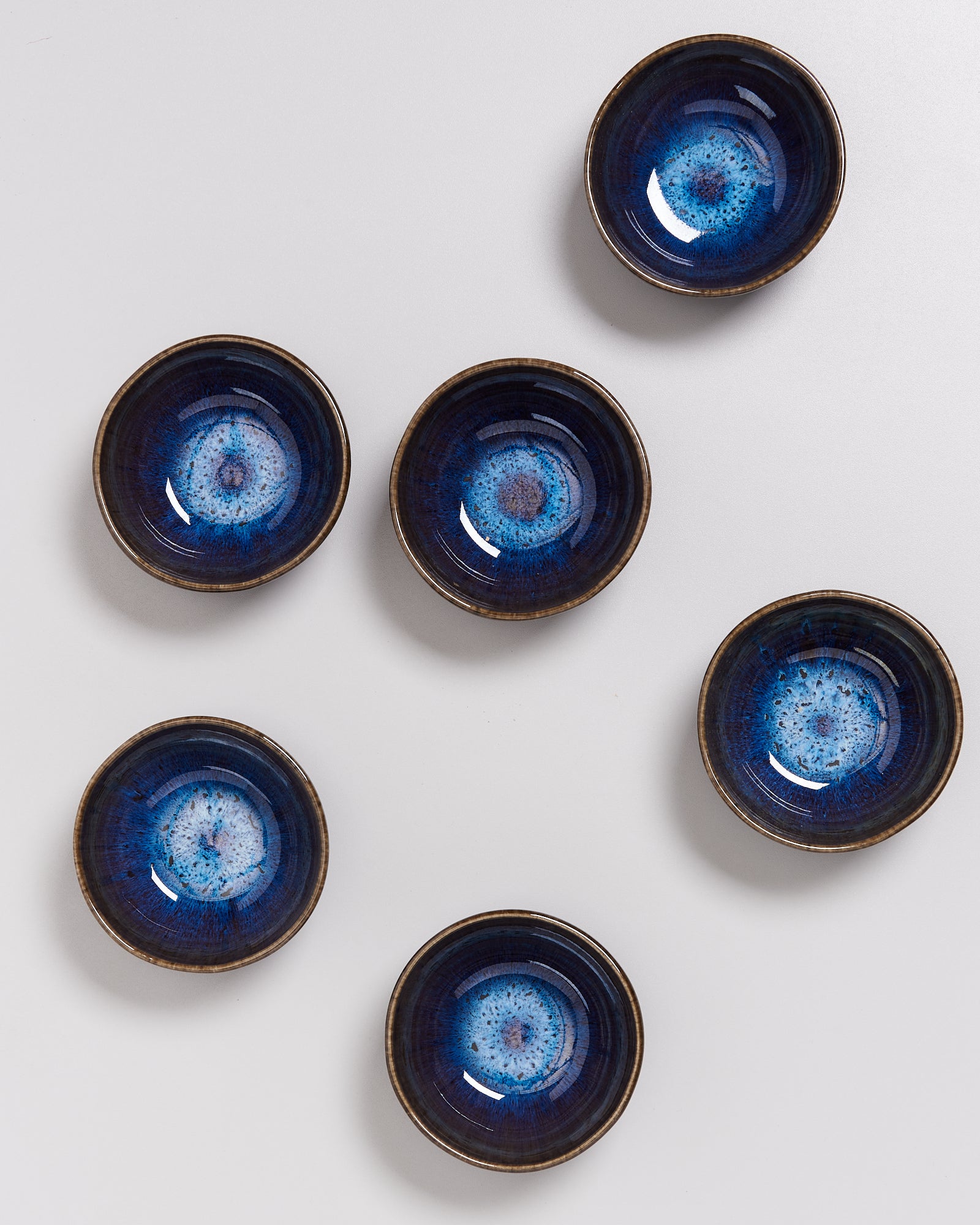 Sechs dunkelblaue Schalen mit einem kreisförmigen Muster auf einer weißen Oberfläche.