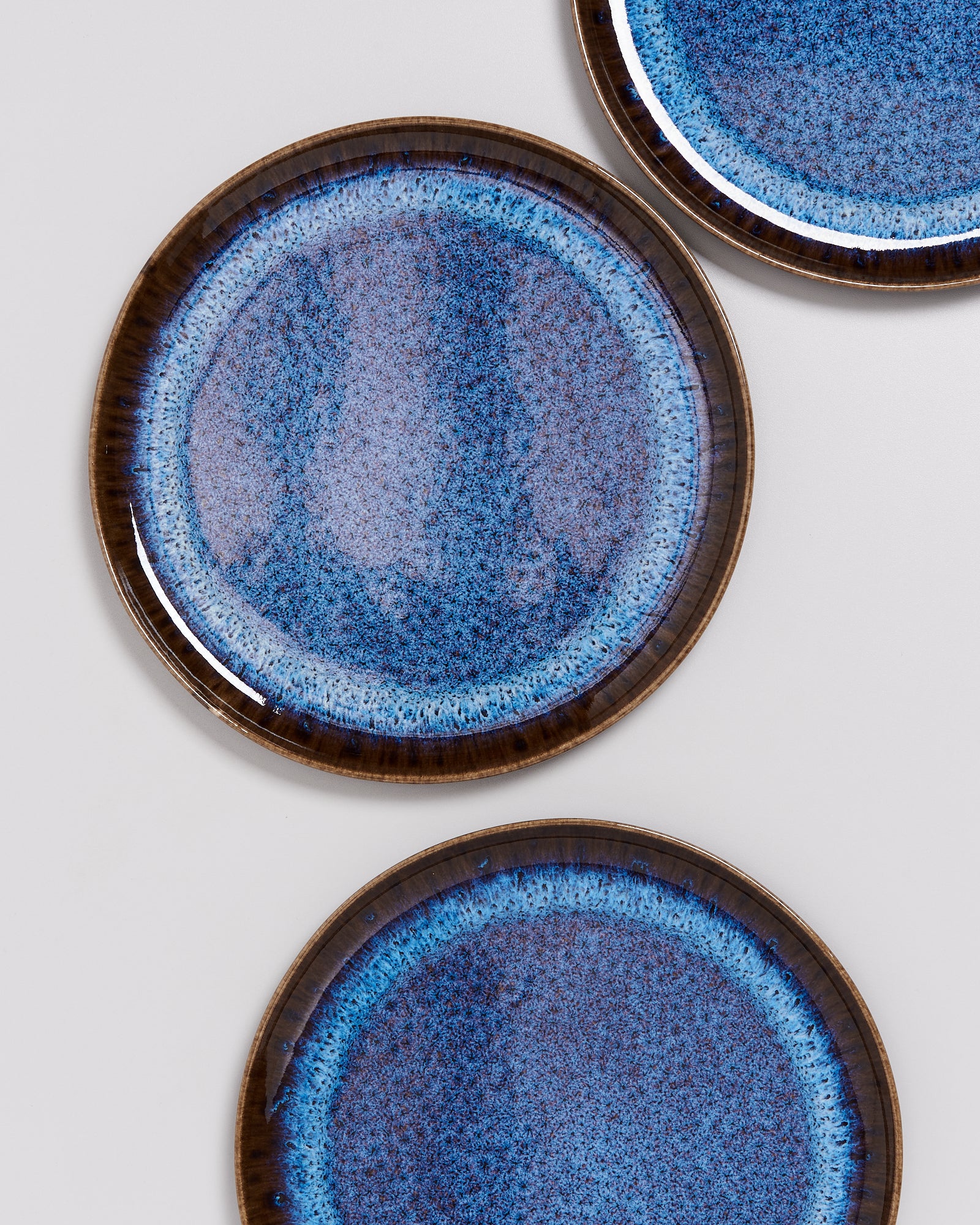 Drei blaue Keramikteller mit einem gesprenkelten Muster auf hellem Hintergrund.