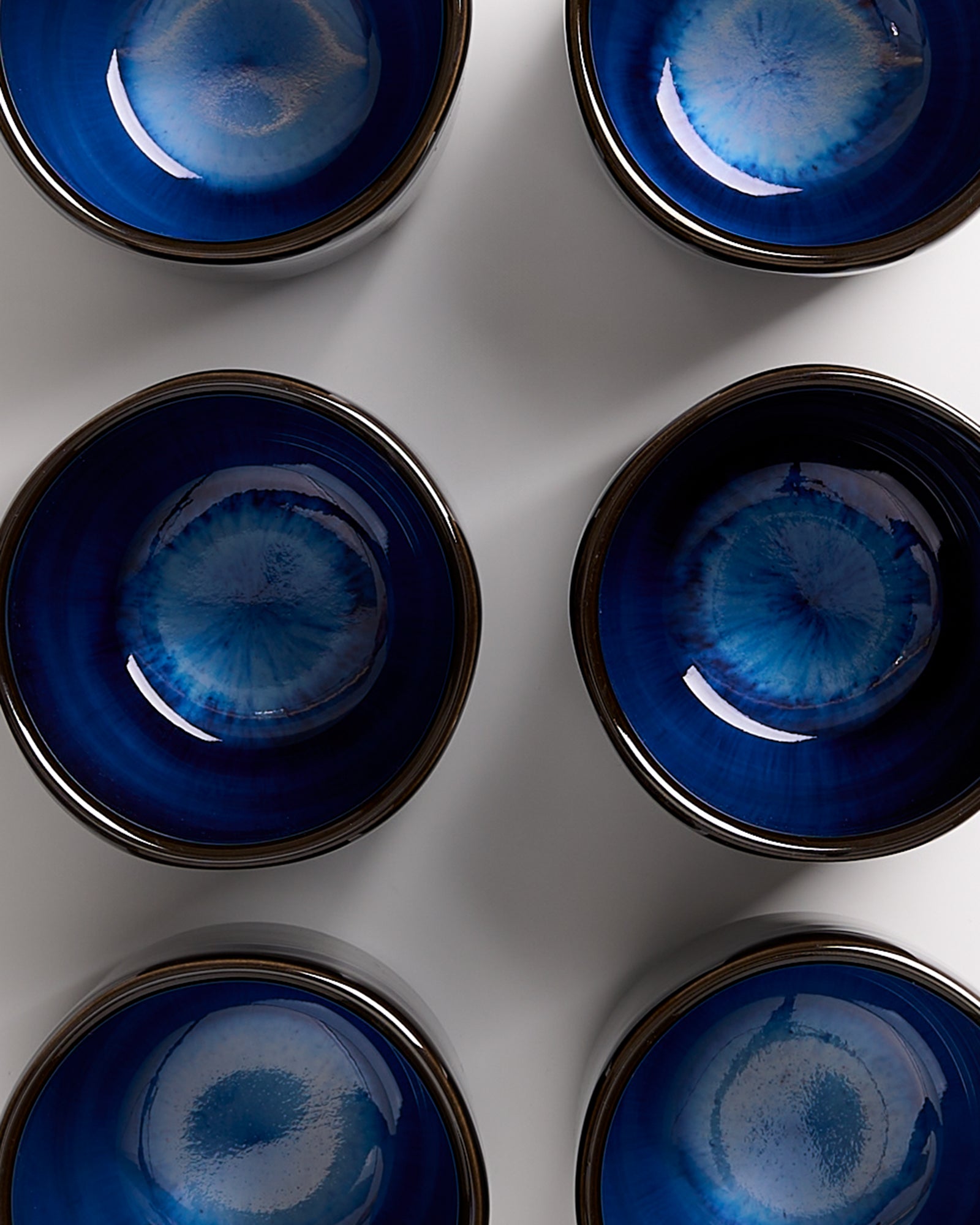 Sechs blaue Schalen mit dunklem Rand auf weißem Hintergrund in zwei Reihen angeordnet.