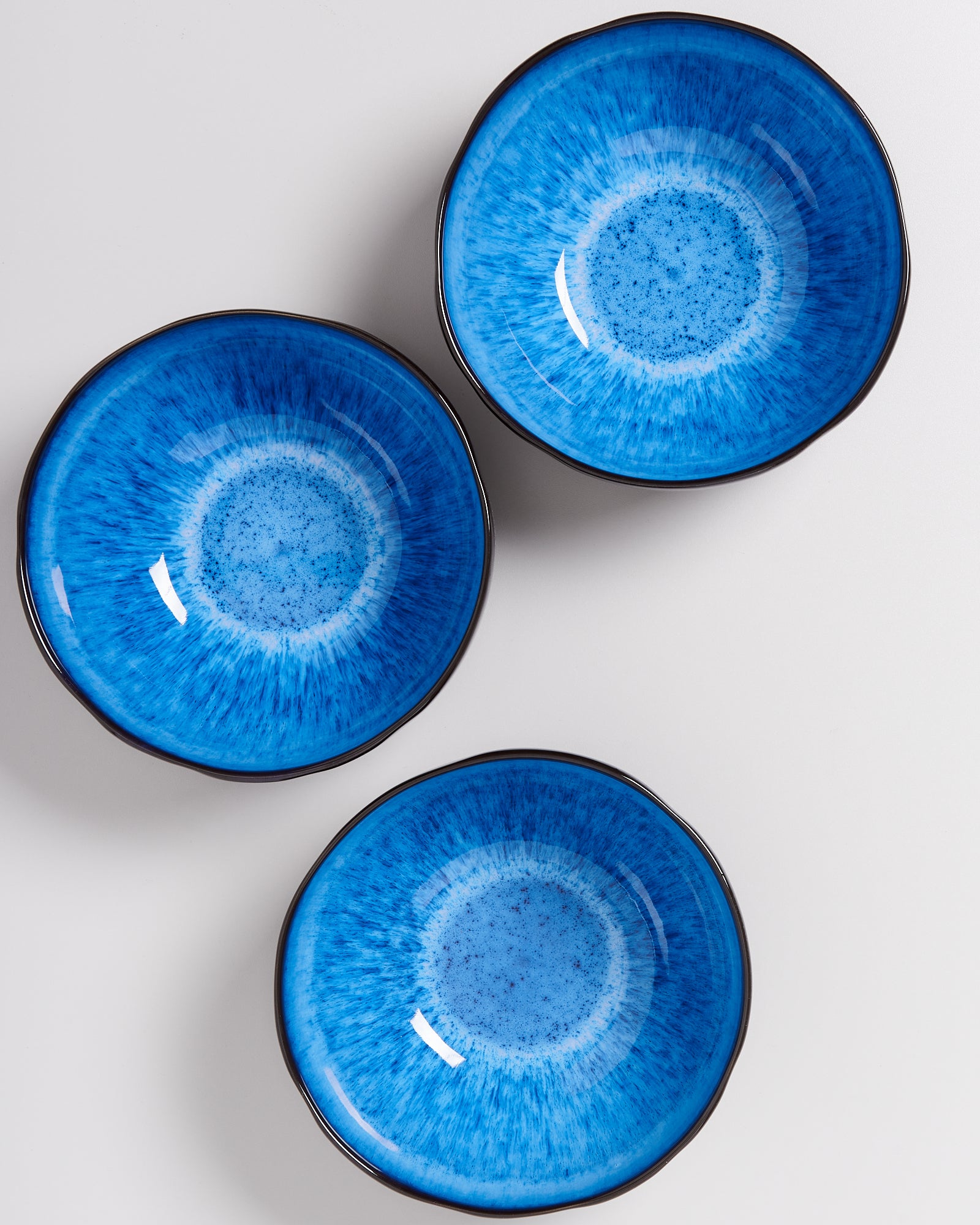 Drei blaue Schalen mit einem weißblauen spiralförmigen Muster auf einer weißen Oberfläche.