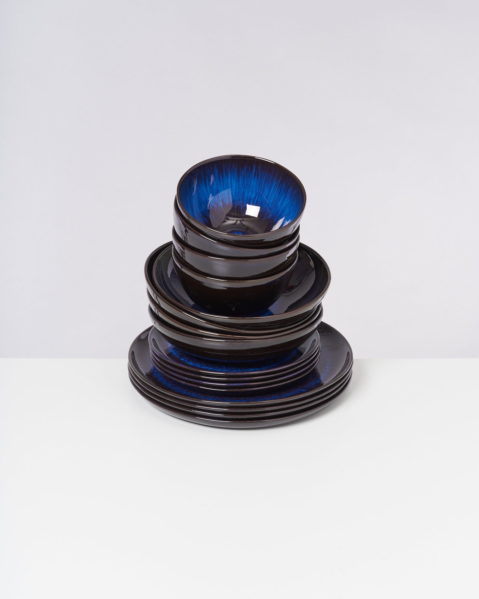 Ein Stapel aus schwarzem Geschirr mit blauem Inneren auf einem weißen Hintergrund.