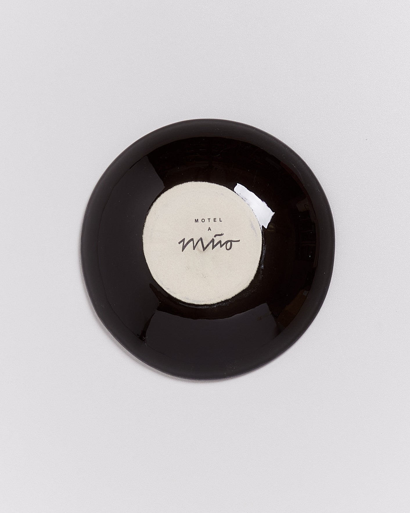 Schwarze, glänzende Schale mit einem weißen Kreis in der Mitte, auf dem "Motel a Mío" steht.