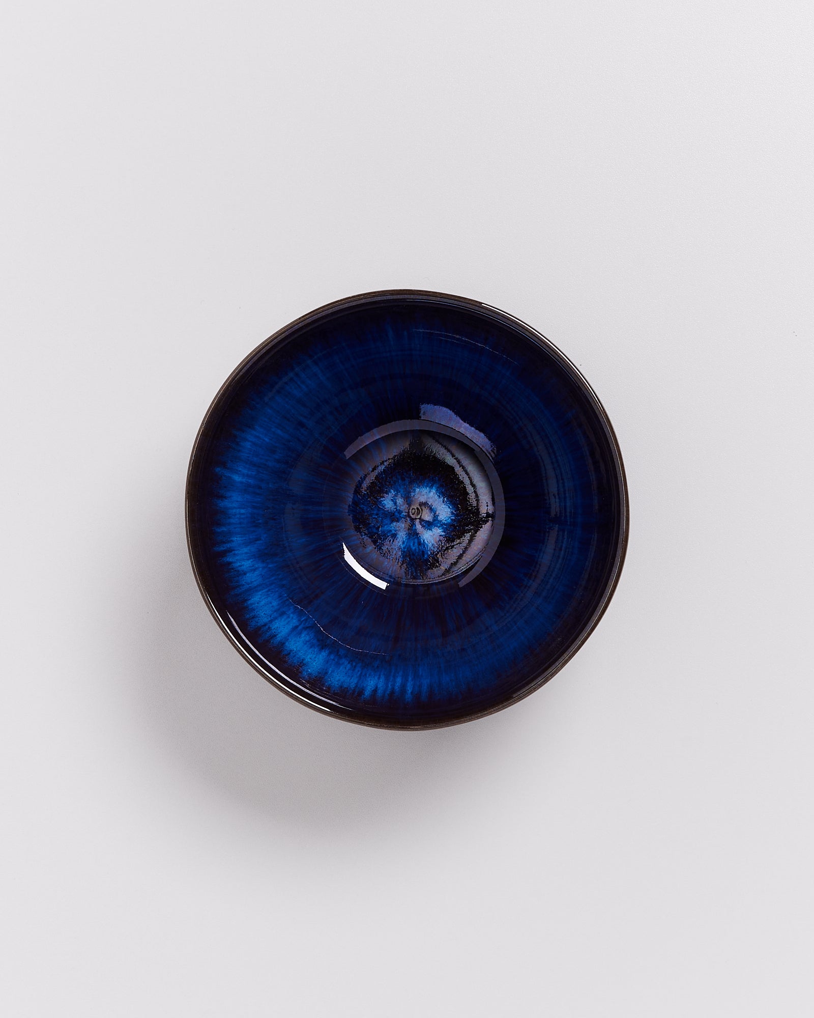 Blau und schwarz glasierte Keramikschale auf weißem Hintergrund.