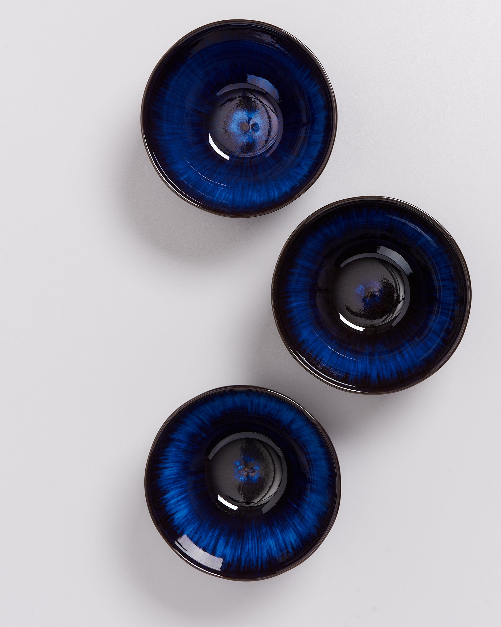 Drei schwarze Schalen mit blauem Muster auf einem weißen Hintergrund.