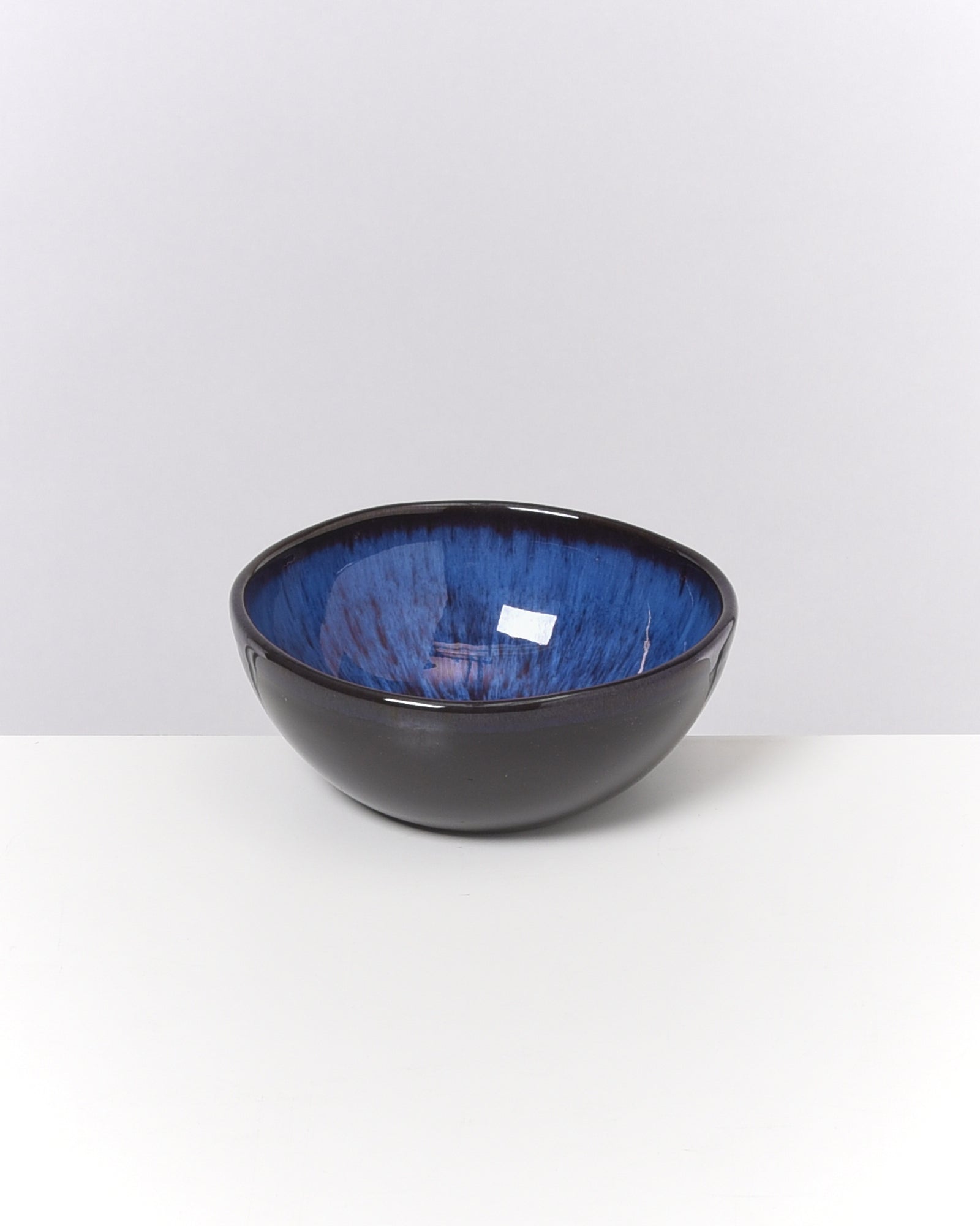 Schwarze Schüssel mit blauer Innenseite auf einem weißen Hintergrund.