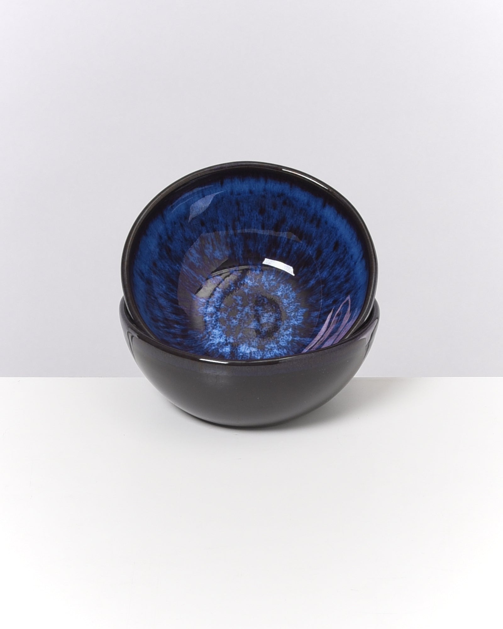 Zwei ineinander gestapelte Schalen mit glänzend blauen Innenseiten auf weißem Hintergrund.