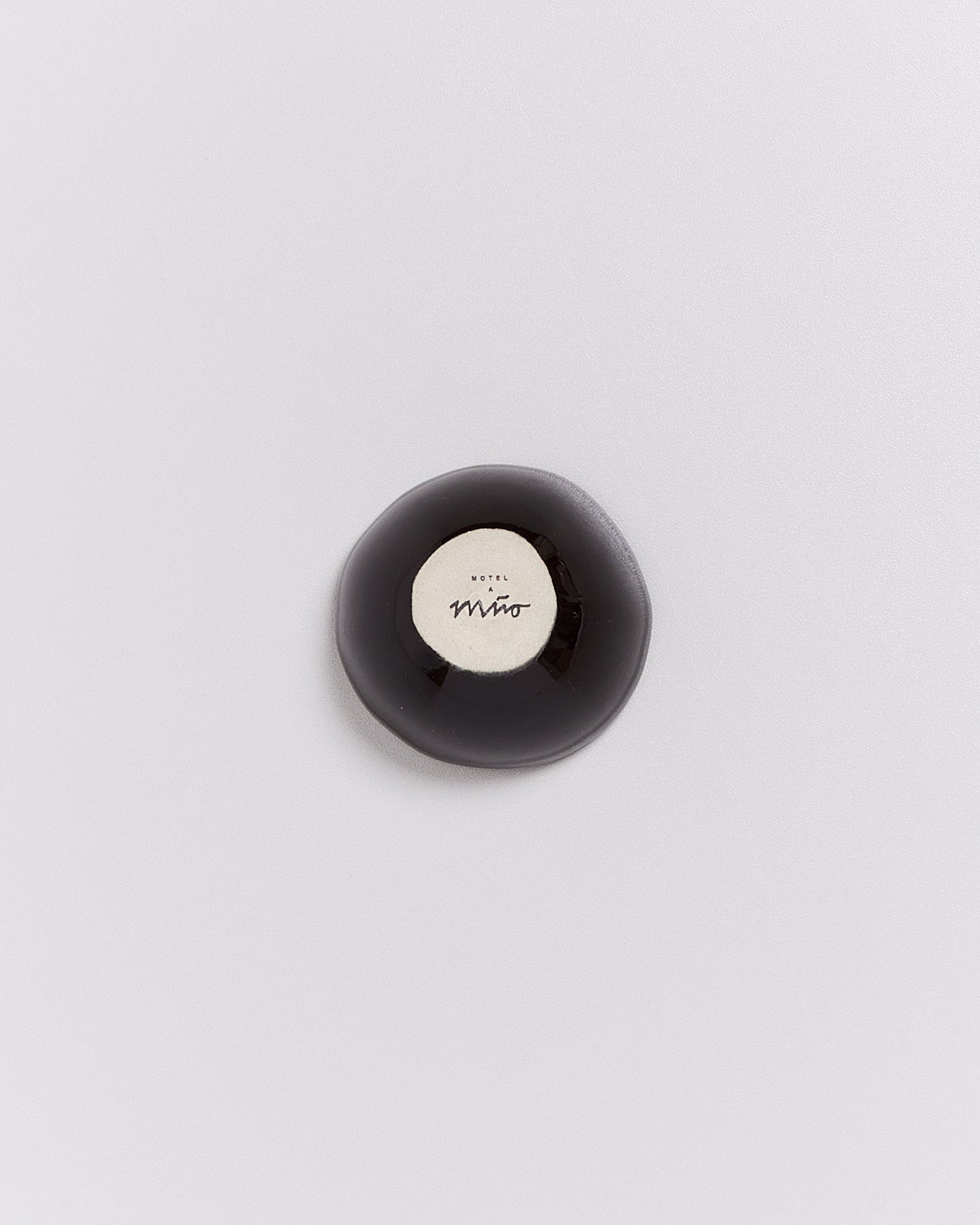 Schwarze, runde Seife mit der Aufschrift „Motel a Mío“ auf weißem Hintergrund.