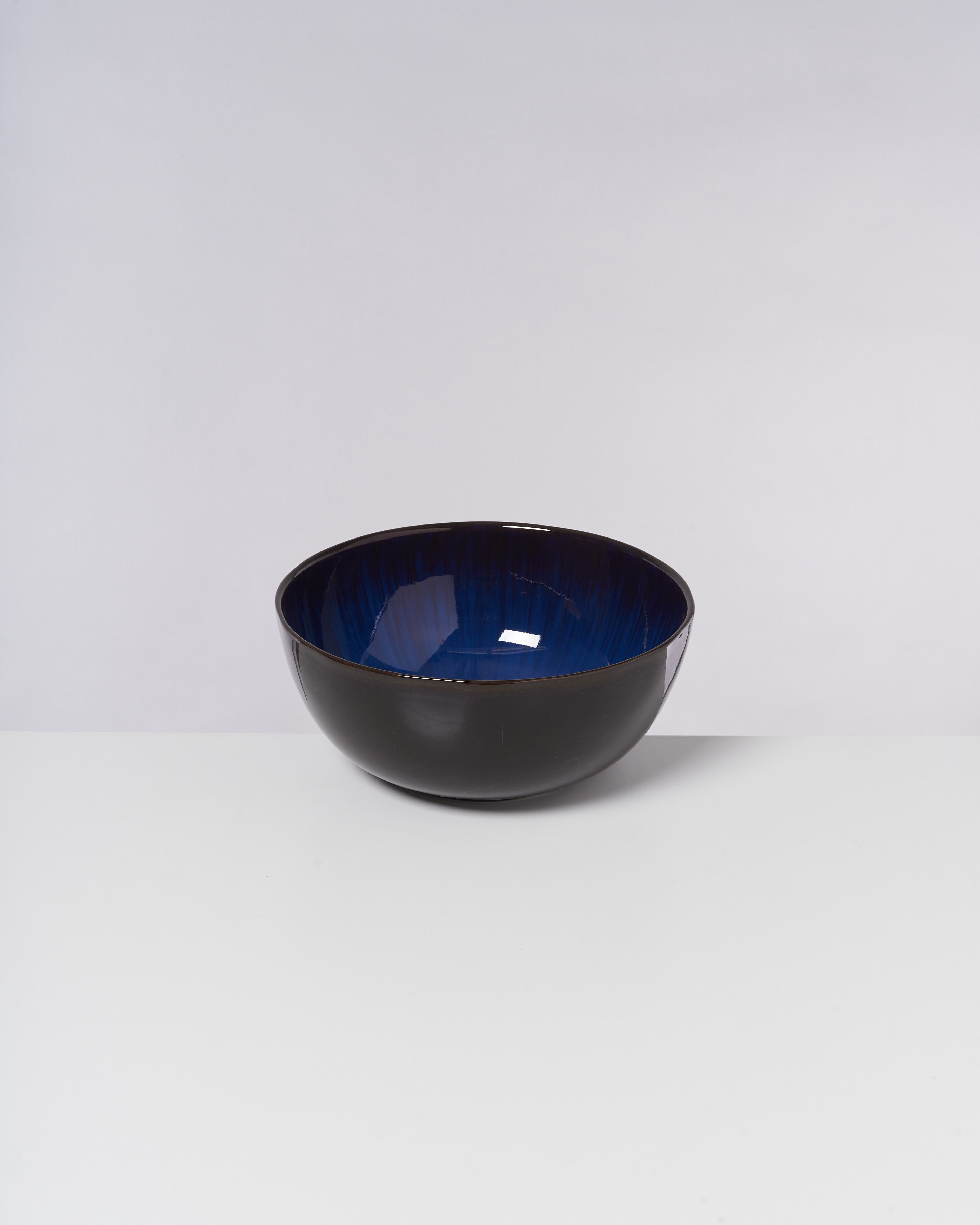 Schwarze Schüssel mit tiefblauer Innenseite auf einem weißen Hintergrund.