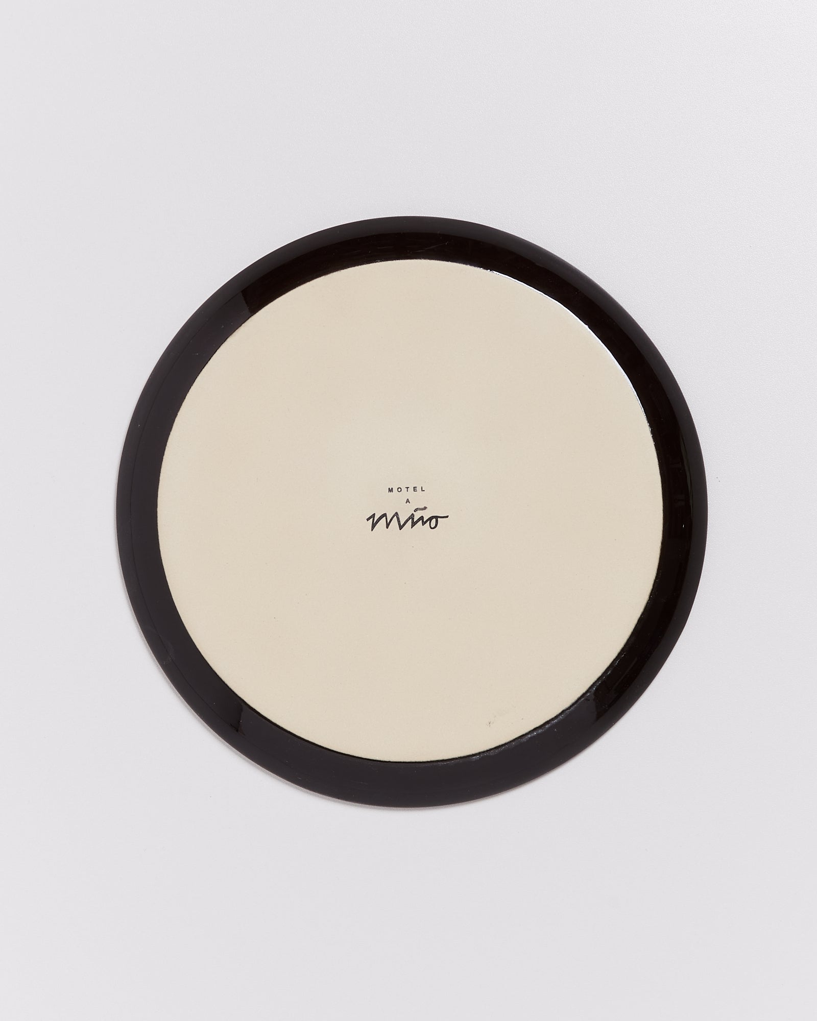 Beige Teller mit schwarzem Rand und der Aufschrift "Hotel a Mino" in der Mitte.