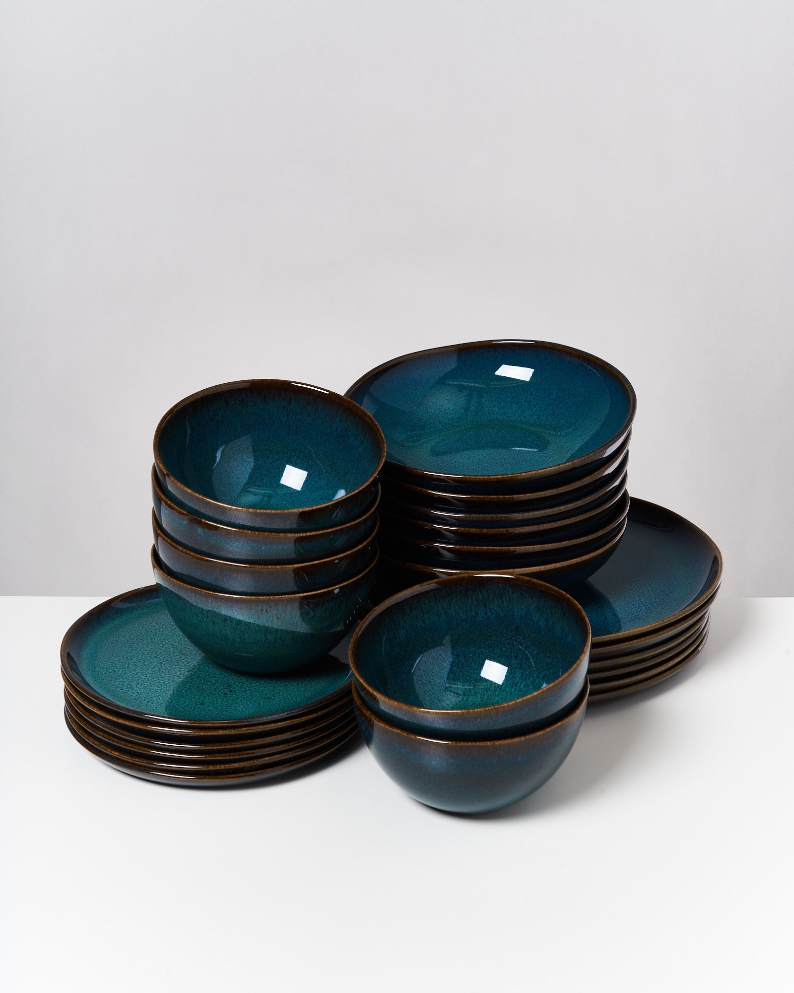 Ein Stapel aus grünen Schalen und Tellern, ordentlich auf einem weißen Tisch angeordnet.