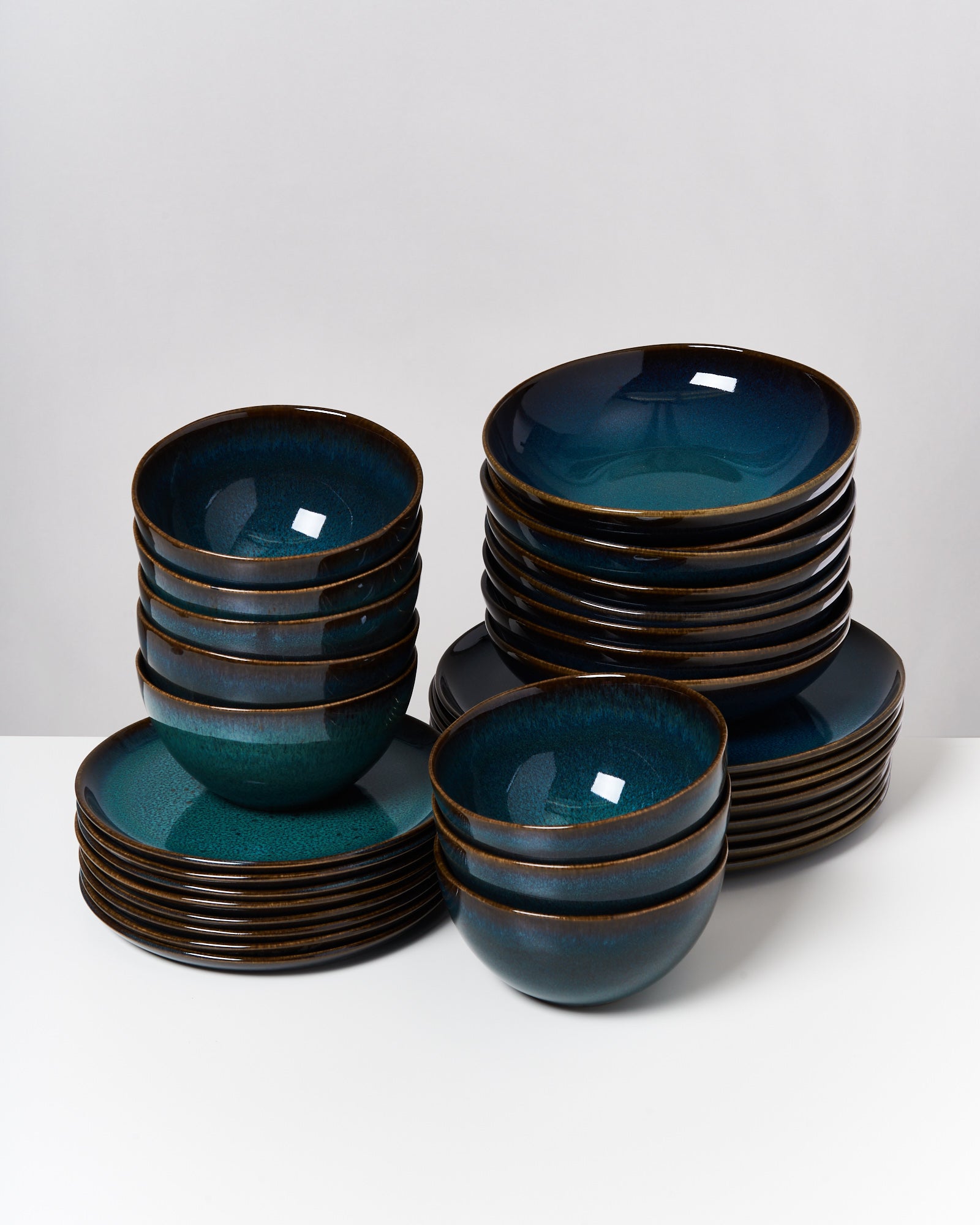 Mehrere Stapel von dunkelblauen Keramiktellern und -schüsseln auf einem weißen Hintergrund.