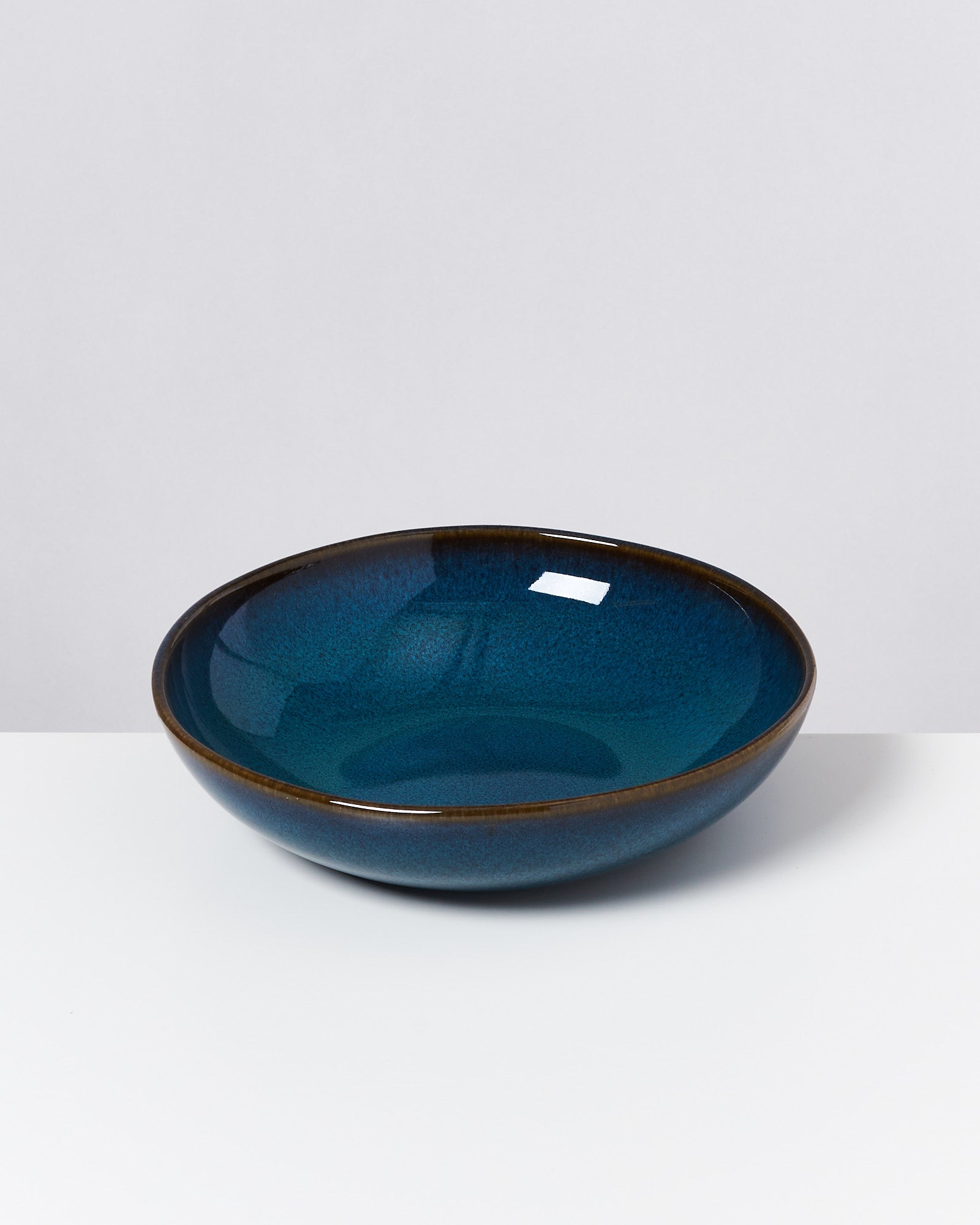 Eine dunkelblaue, runde Keramikschale mit glasiertem Finish auf weißem Hintergrund.