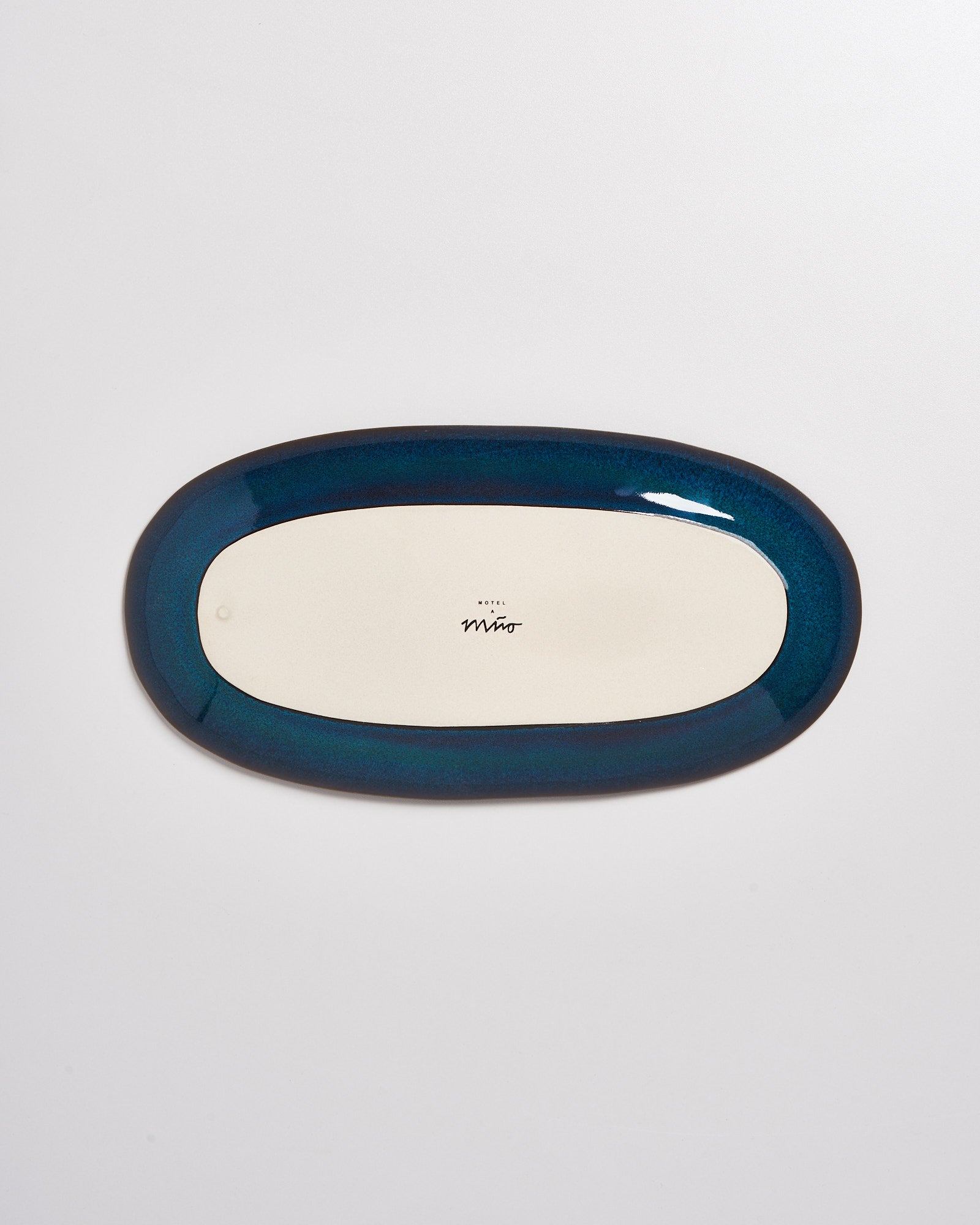 Ovaler Teller mit blauem Rand, von oben fotografiert, mit Logo in der Mitte auf der Unterseite.