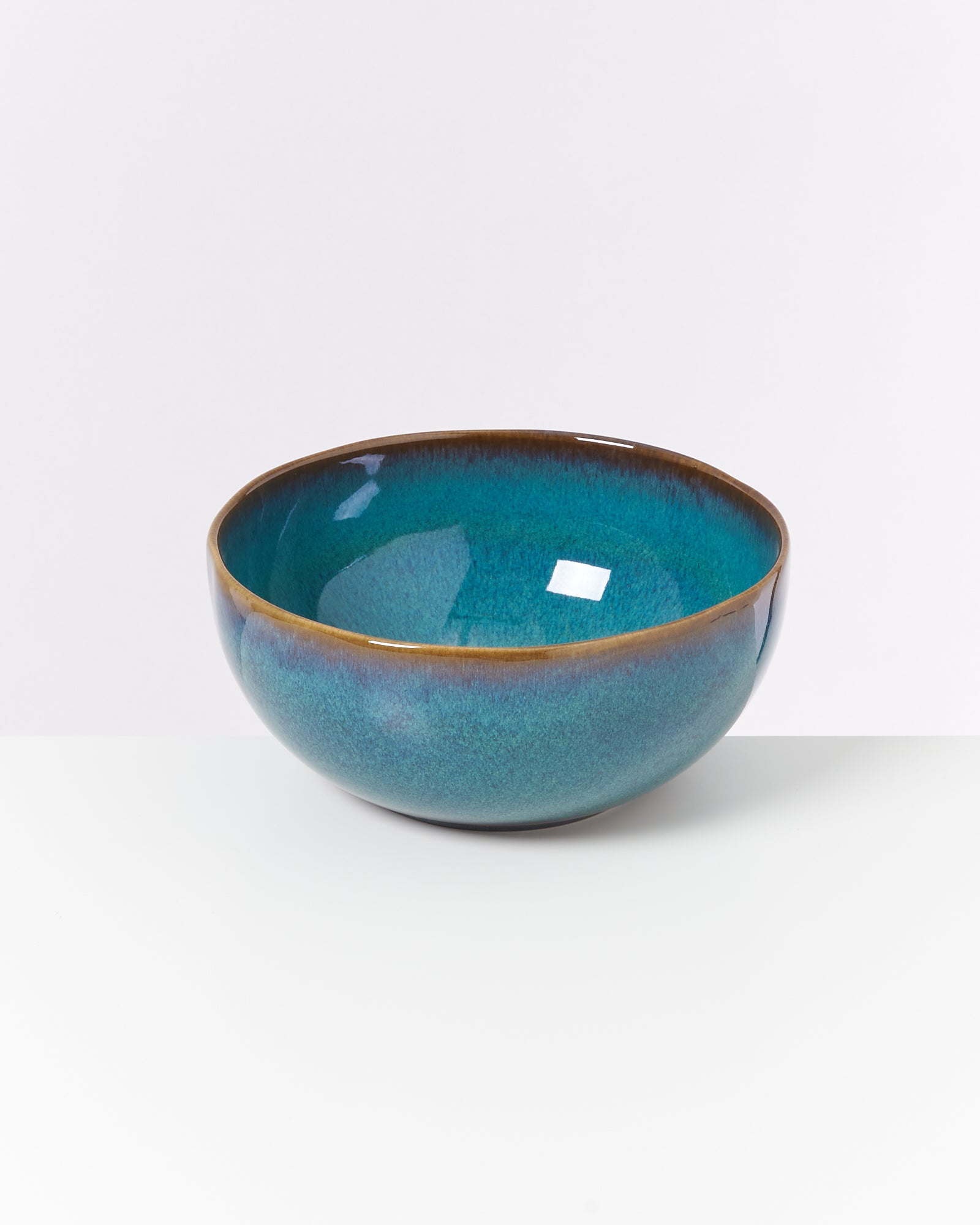 Blau-grüne keramikschale auf weißem Hintergrund.