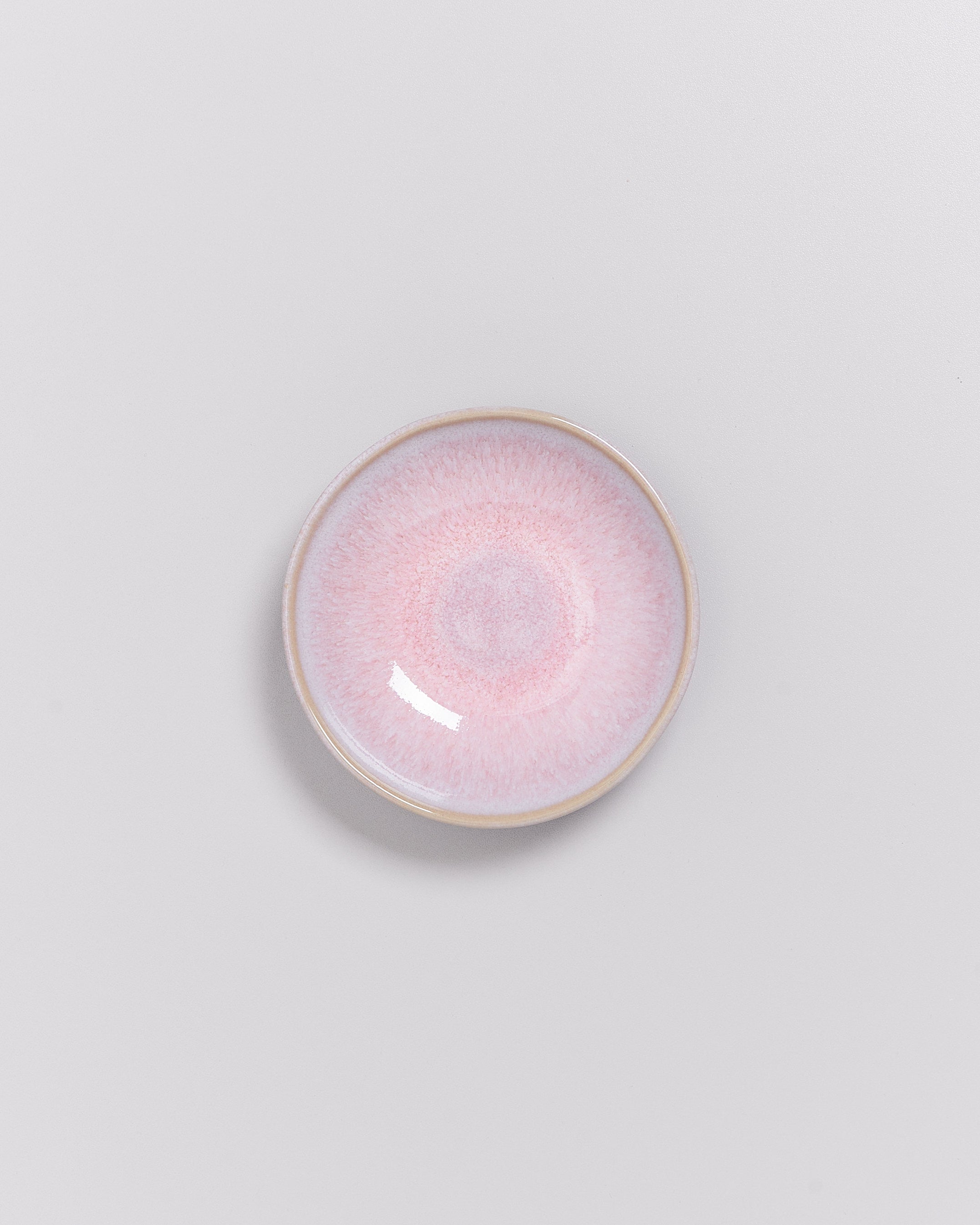 Keramikteller mit rosa Farbverlauf auf grauem Hintergrund.