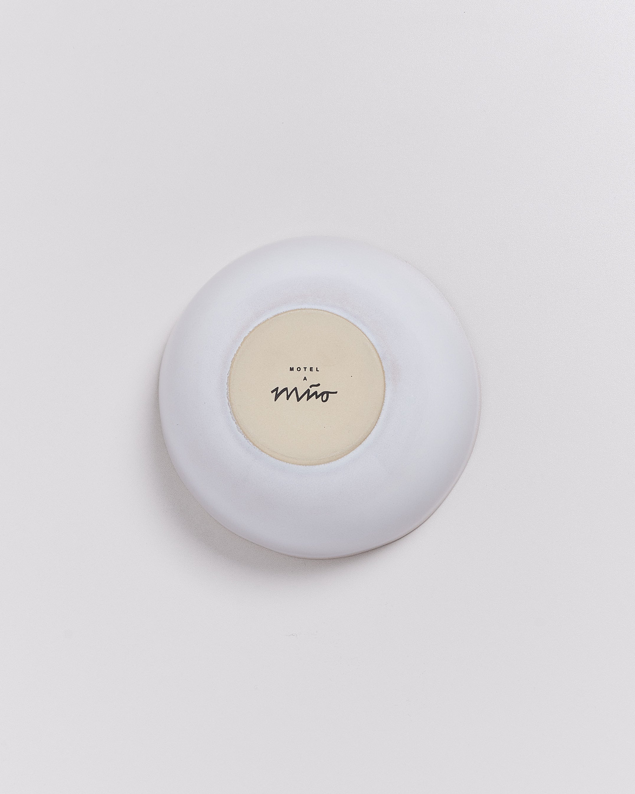Weiße Schale auf hellem Hintergrund, Boden markiert mit "Motel a Miio".