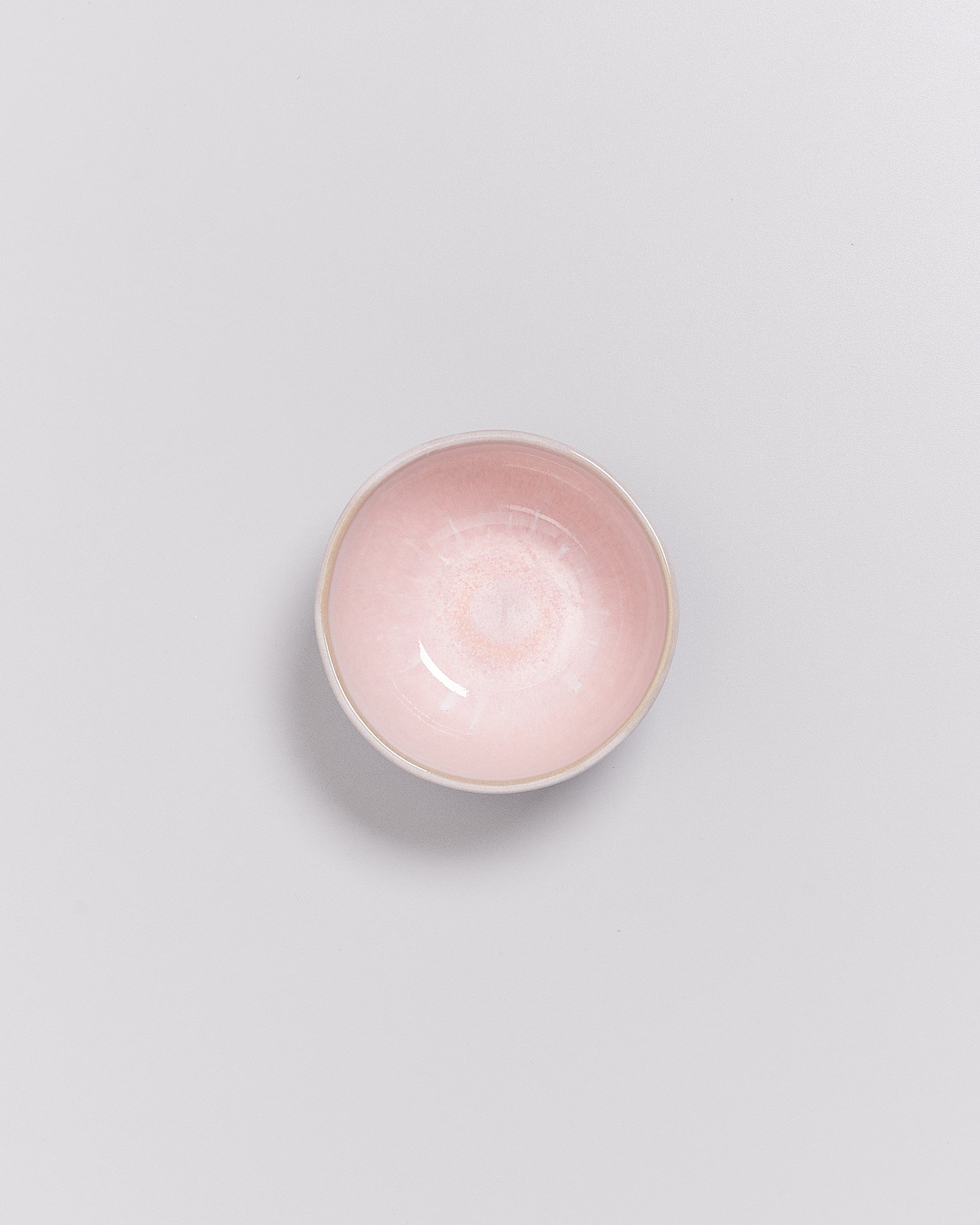 Rosa Keramikschale auf weißem Hintergrund, von oben betrachtet.