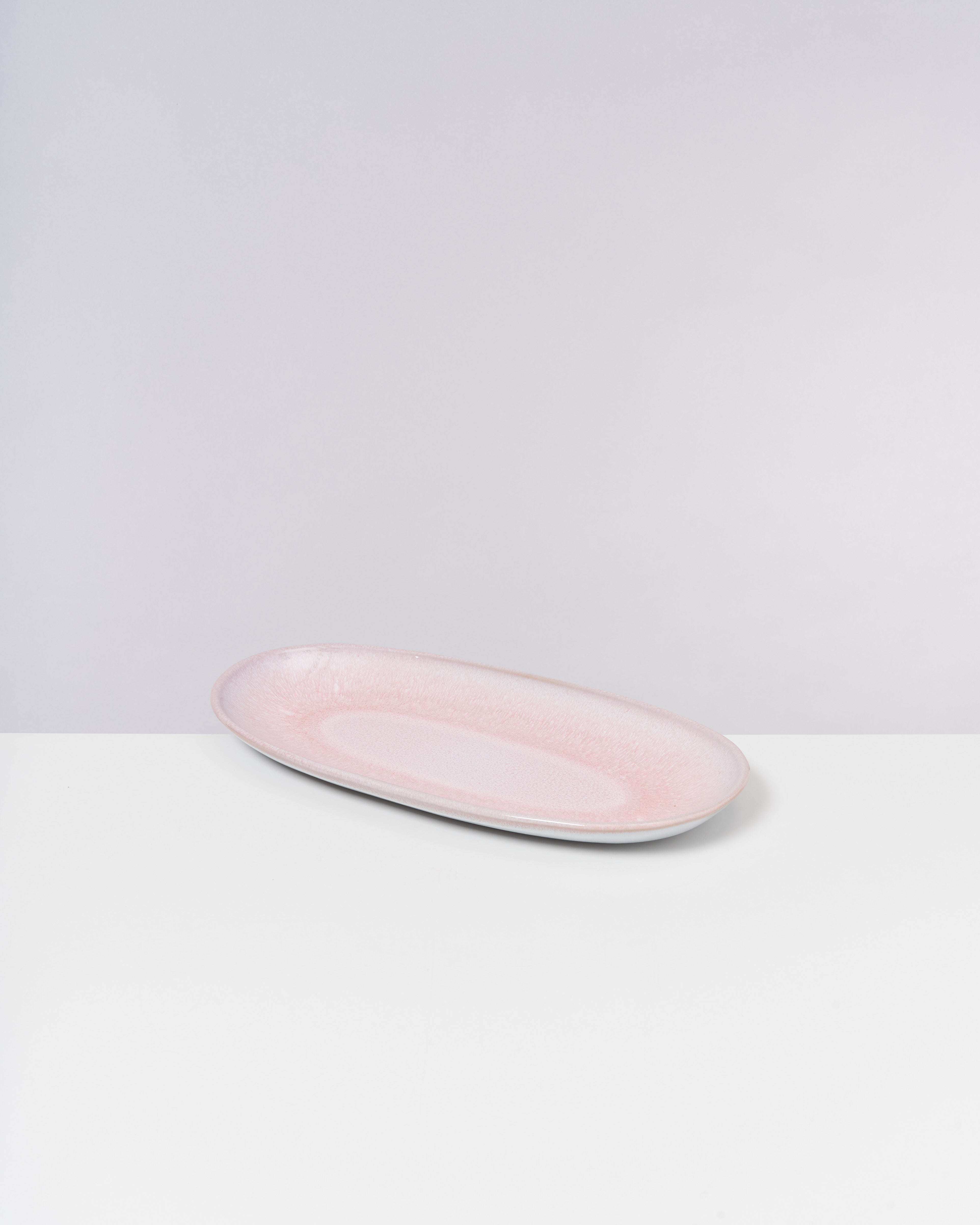 Rosa, ovaler Teller auf weißem Hintergrund.