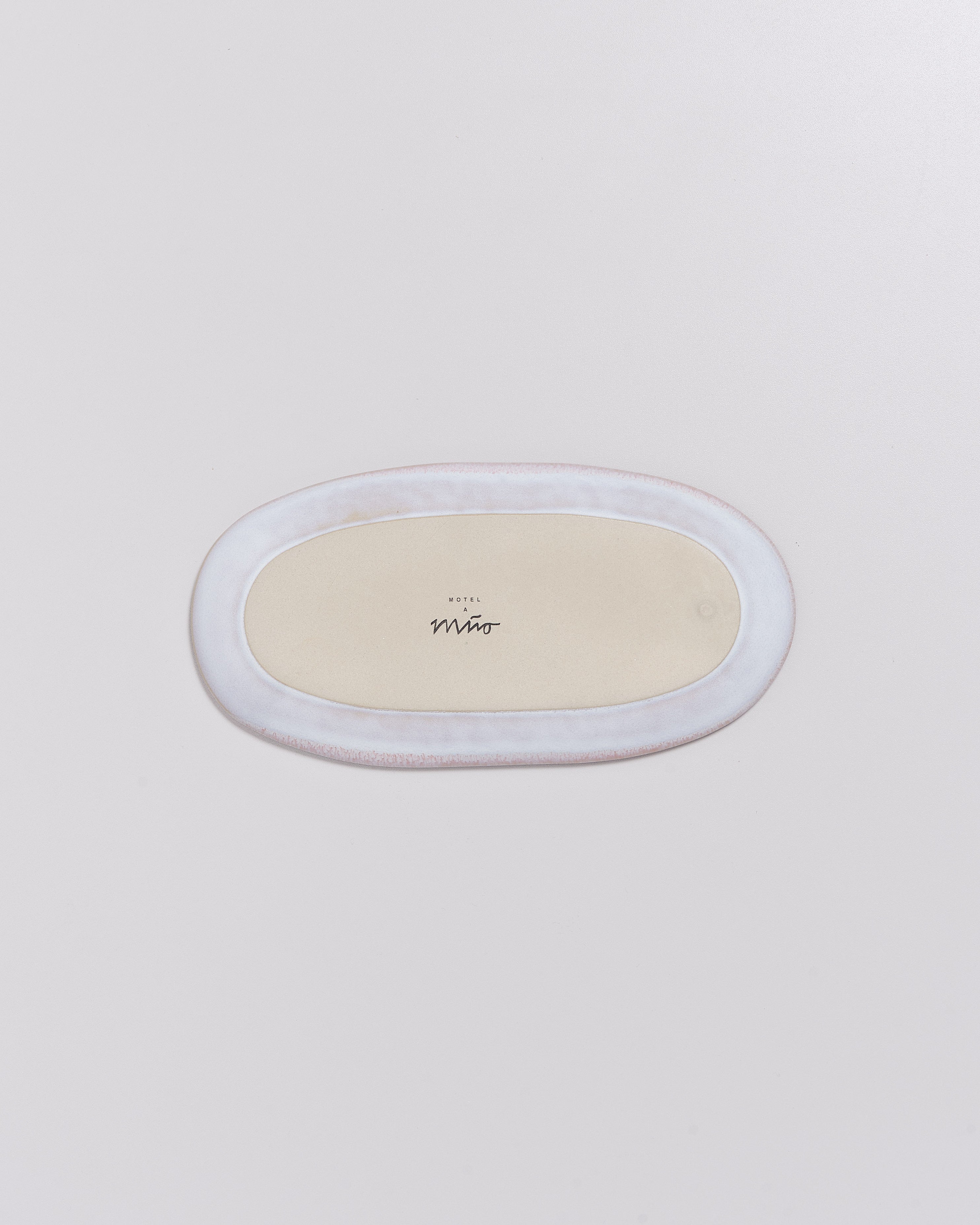 Ovaler Keramikteller mit Schriftzug "HOTEL A Mio" auf der Unterseite, vor einem hellen Hintergrund.