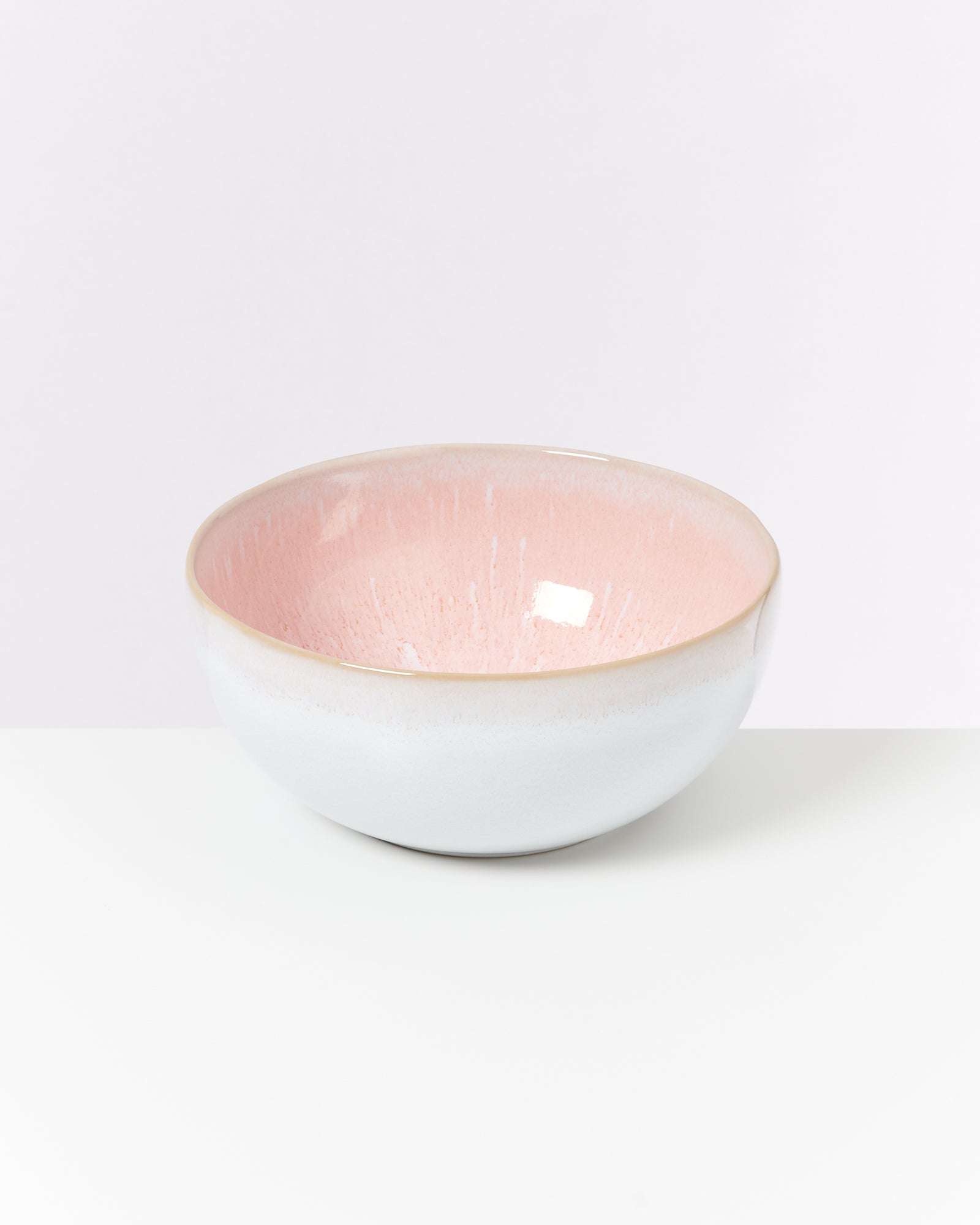 Keramikschüssel mit rosa Innenseite und weißer Außenseite steht auf einem weißen Hintergrund.
