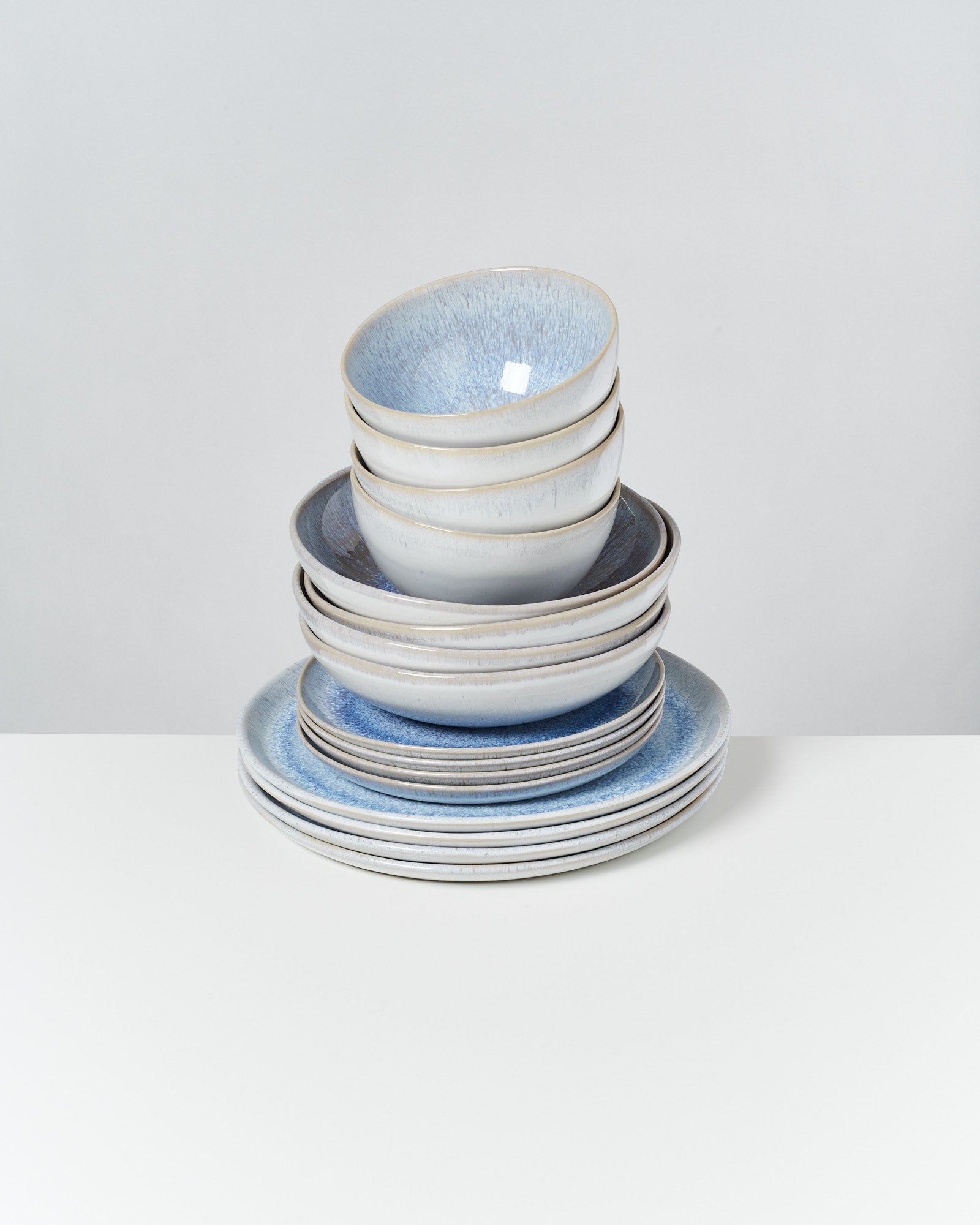 Ein stapel Geschirr bestehend aus blauen und weißen Tellern und Schalen auf einer weißen Oberfläche.