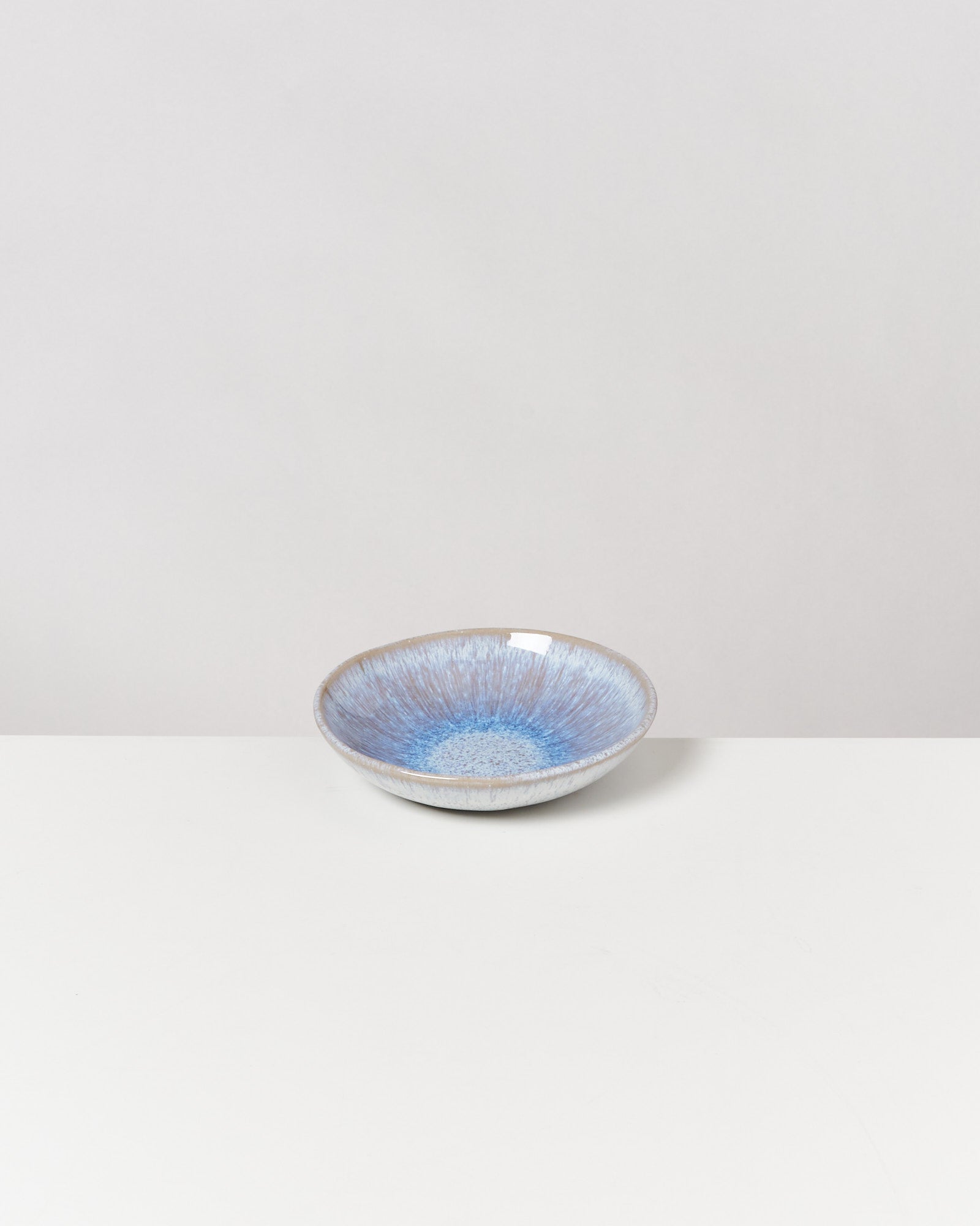 Keramikschale mit blauem, gesprenkeltem Muster auf weißem Hintergrund.